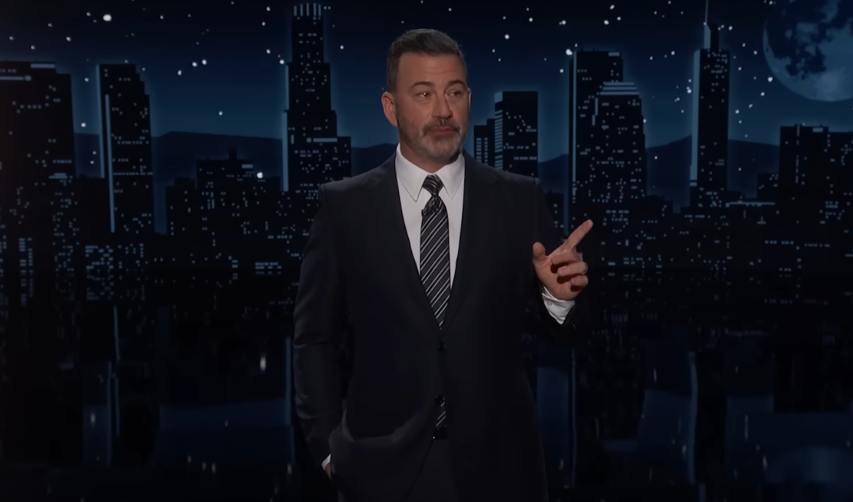 A idiosyncratic   successful  a suit   and necktie  stands connected  a signifier    earlier  a cityscape backdrop with stars, appearing to code  an audience