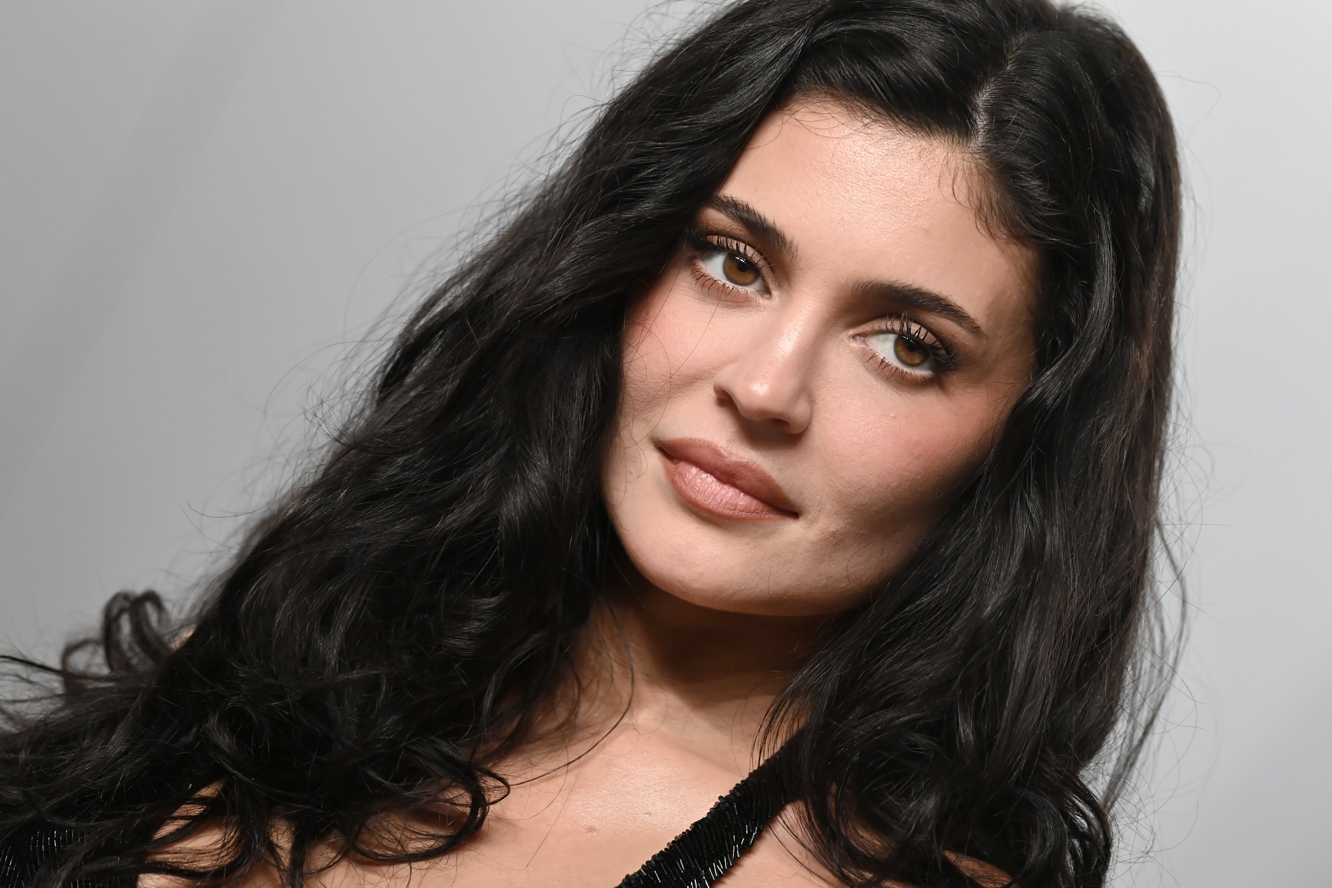 Kylie Jenner with agelong hairsbreadth looks towards the camera, wearing an outfit with a delicate design