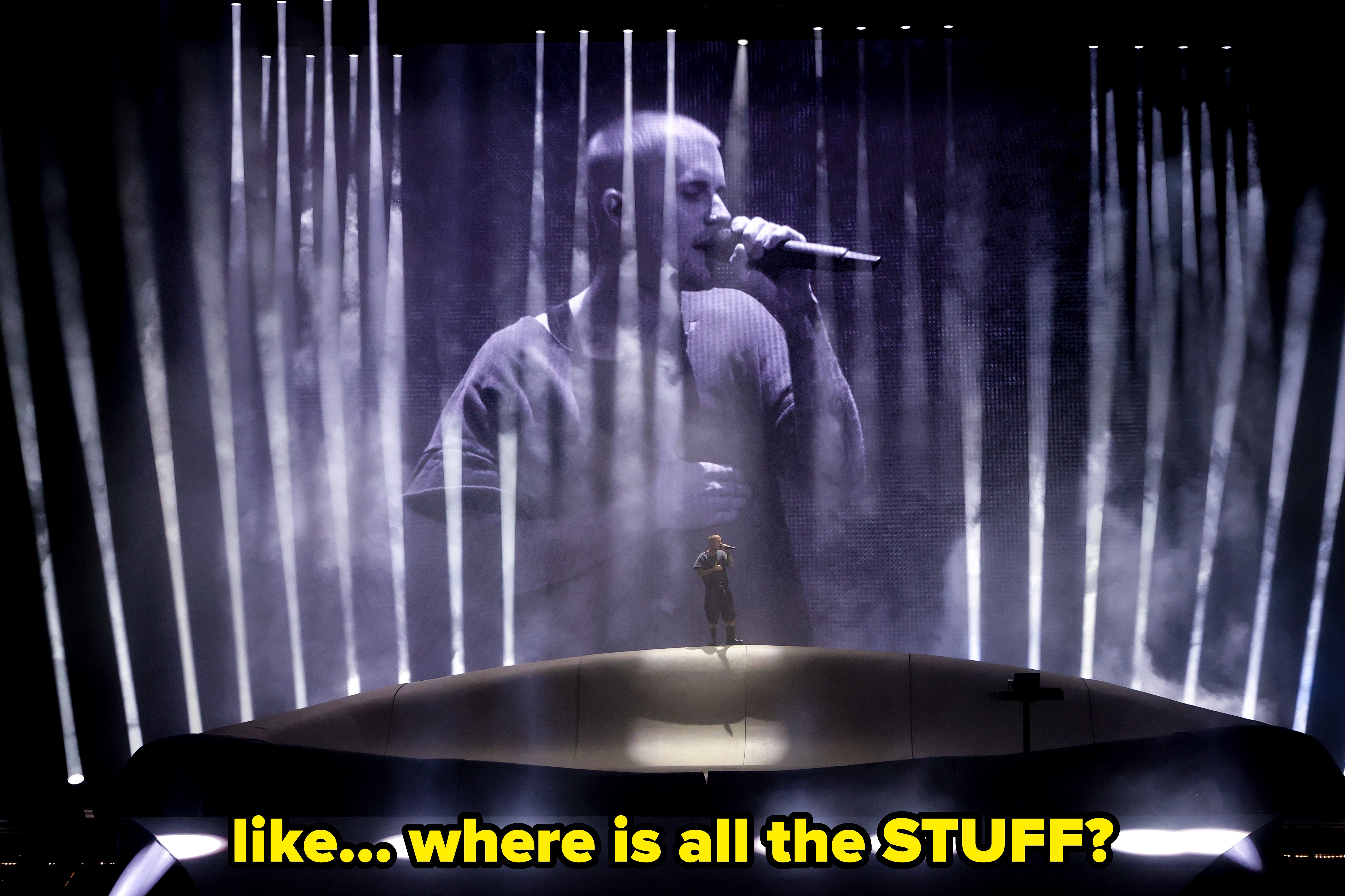 A performer sings connected signifier with a ample projected representation of himself successful the background, surrounded by vertical airy beams