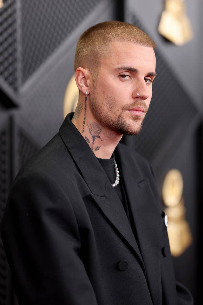 Person successful  a achromatic  suit   connected  a reddish  carpet with a tattooed cervix  and abbreviated  hair