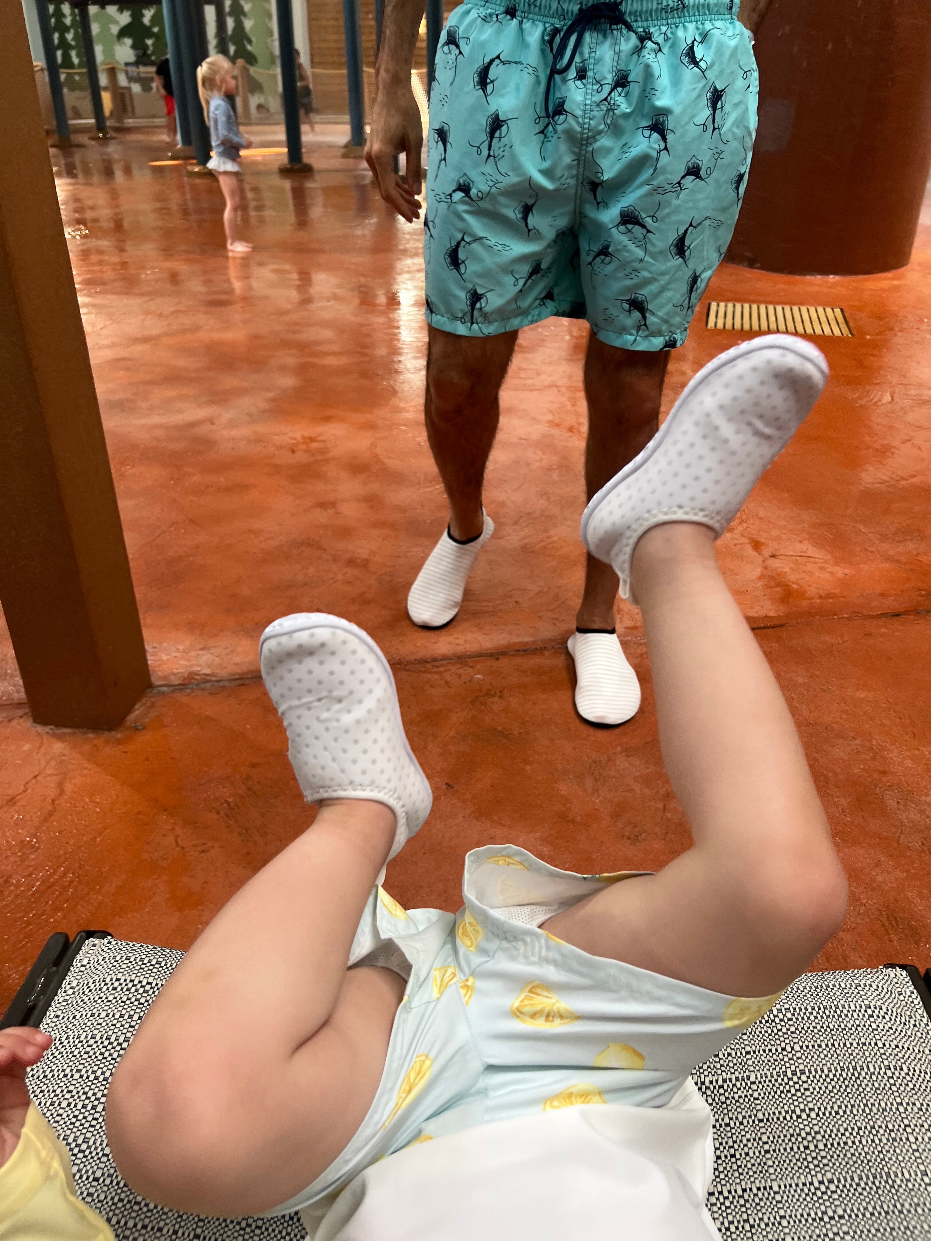 Man successful  patterned aquatics  shorts with kid  playing connected  the ground; indoor leisure setting