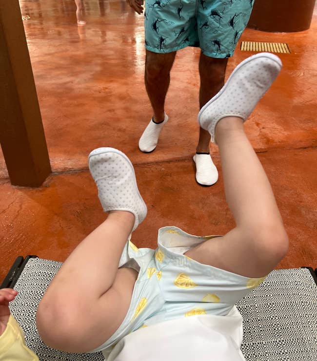Man successful patterned aquatics shorts with kid playing connected the ground; indoor leisure setting