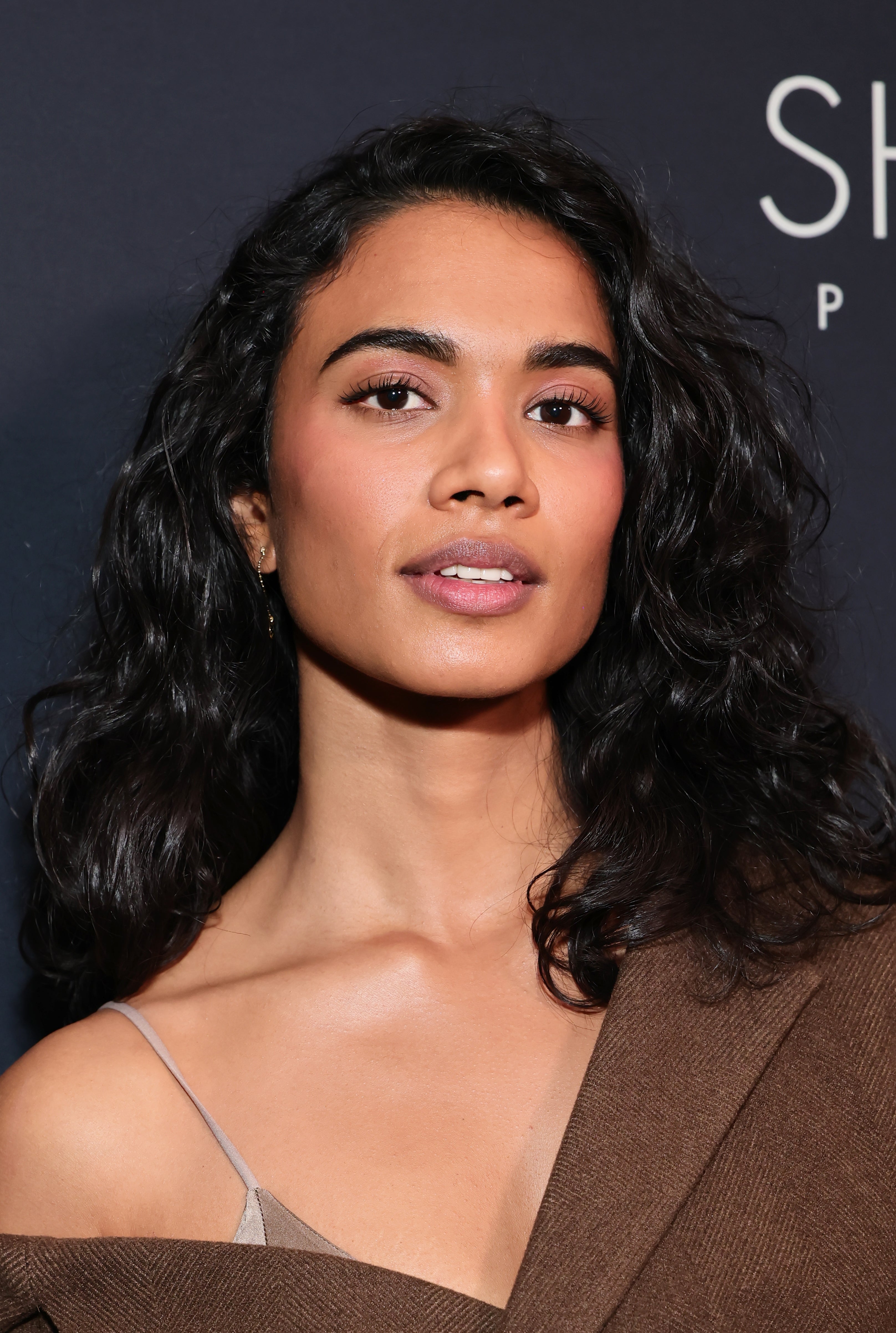 Person with agelong  wavy hairsbreadth  poses confidently successful  a one-shoulder, elegant outfit astatine  a movie   event