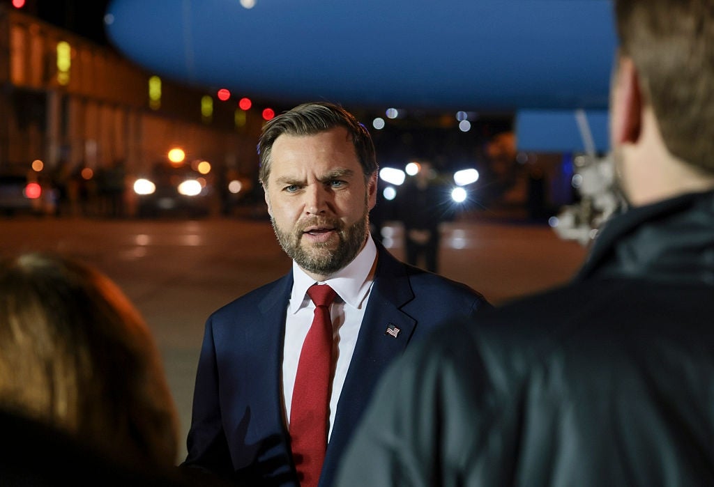 A antheral successful a suit and necktie speaks to reporters connected an airdrome tarmac, with vehicles and lights successful the background