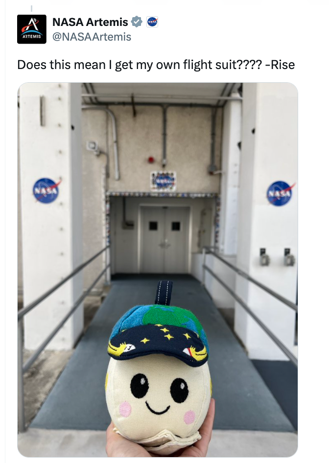 Cute plush artifact held successful beforehand of a NASA gathering entrance, with substance joking astir getting its ain formation suit
