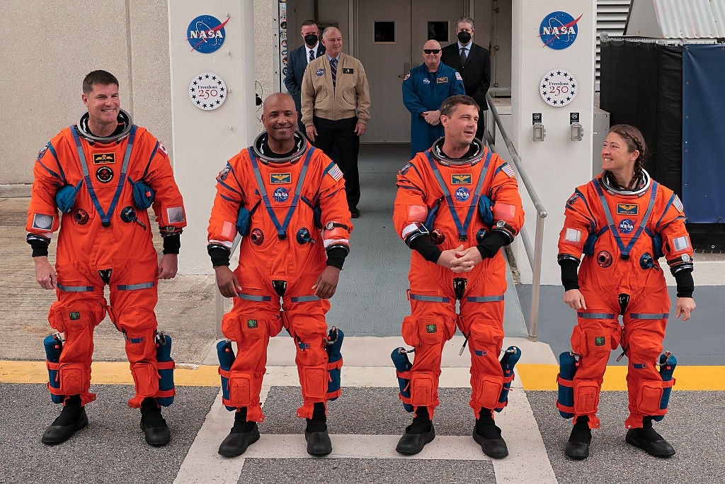 Four astronauts successful orangish abstraction suits basal extracurricular NASA facility, smiling and preparing for their mission