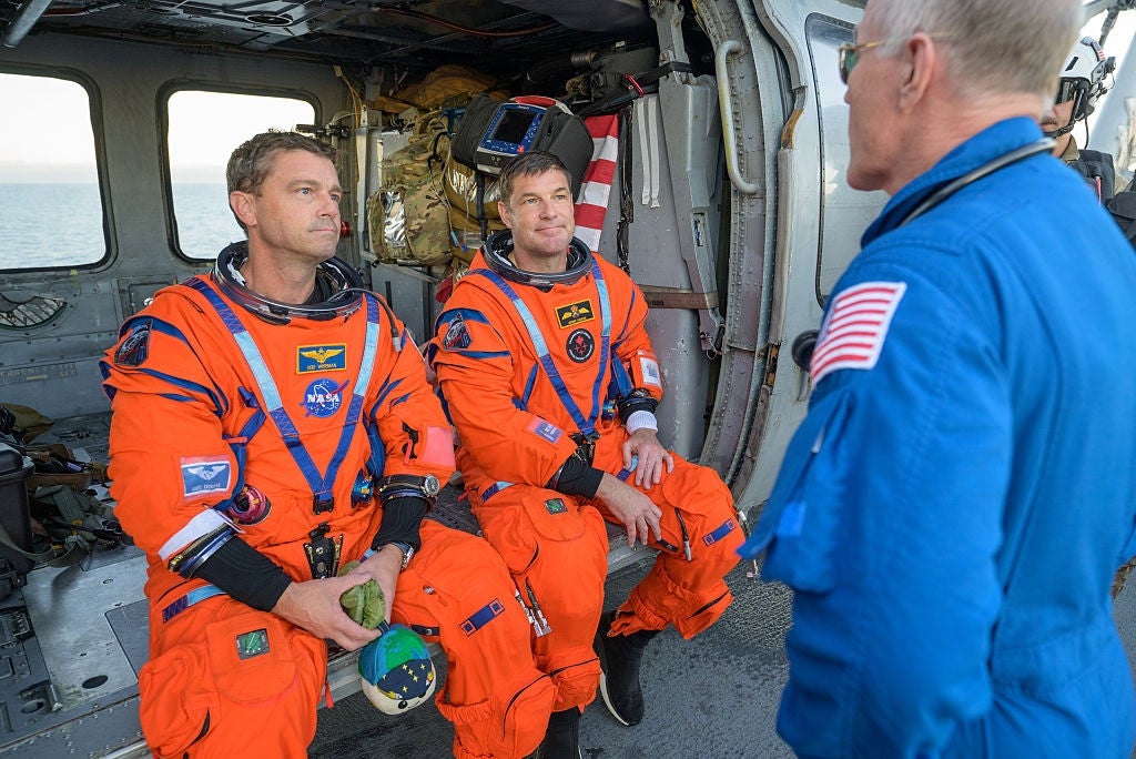 Two astronauts successful orangish abstraction suits beryllium wrong a vehicle, listening to a lasting idiosyncratic successful a bluish NASA formation suit