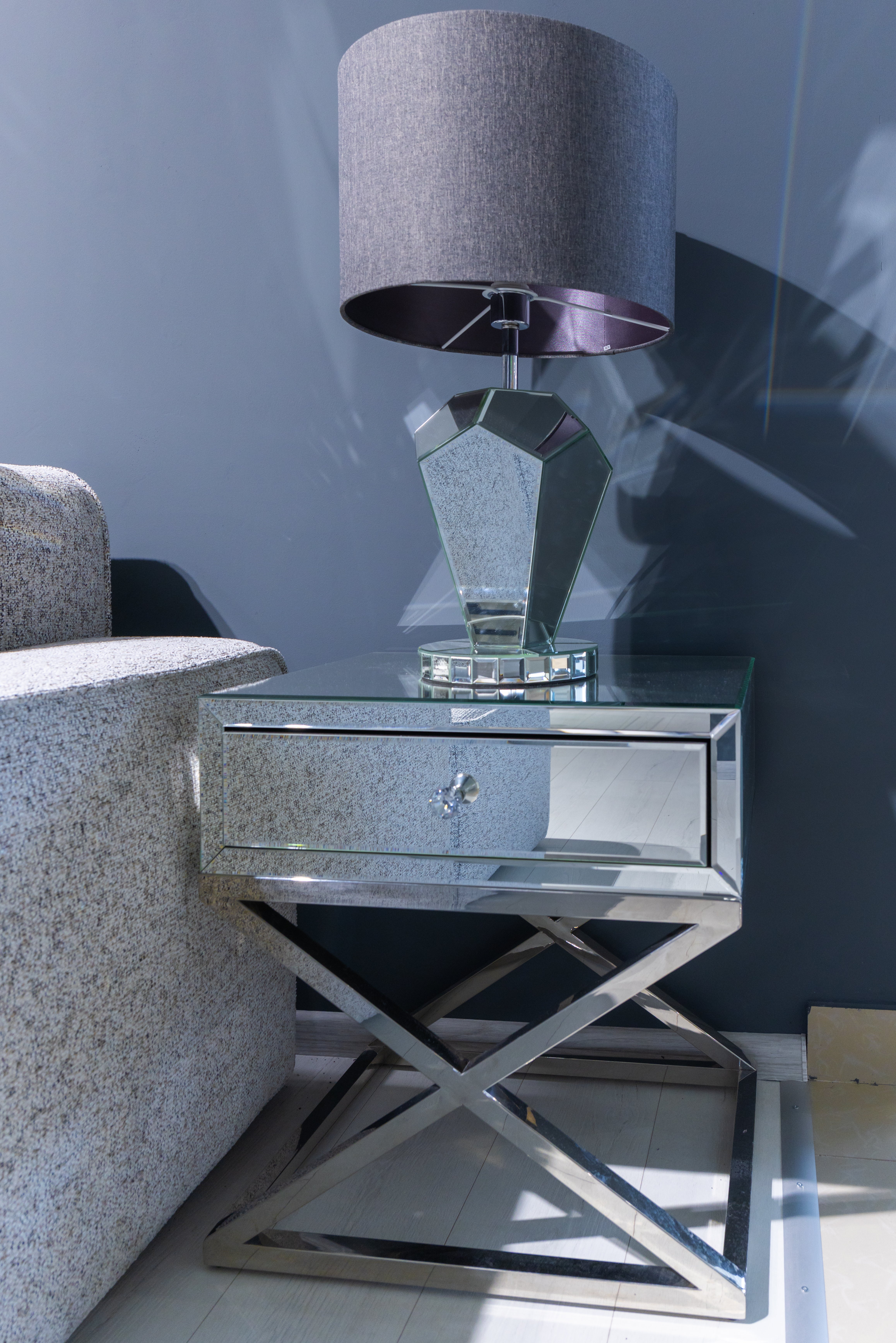 A modern, mirrored broadside  array  with a geometric lamp placed beside a sofa successful  a stylish surviving  country   setting