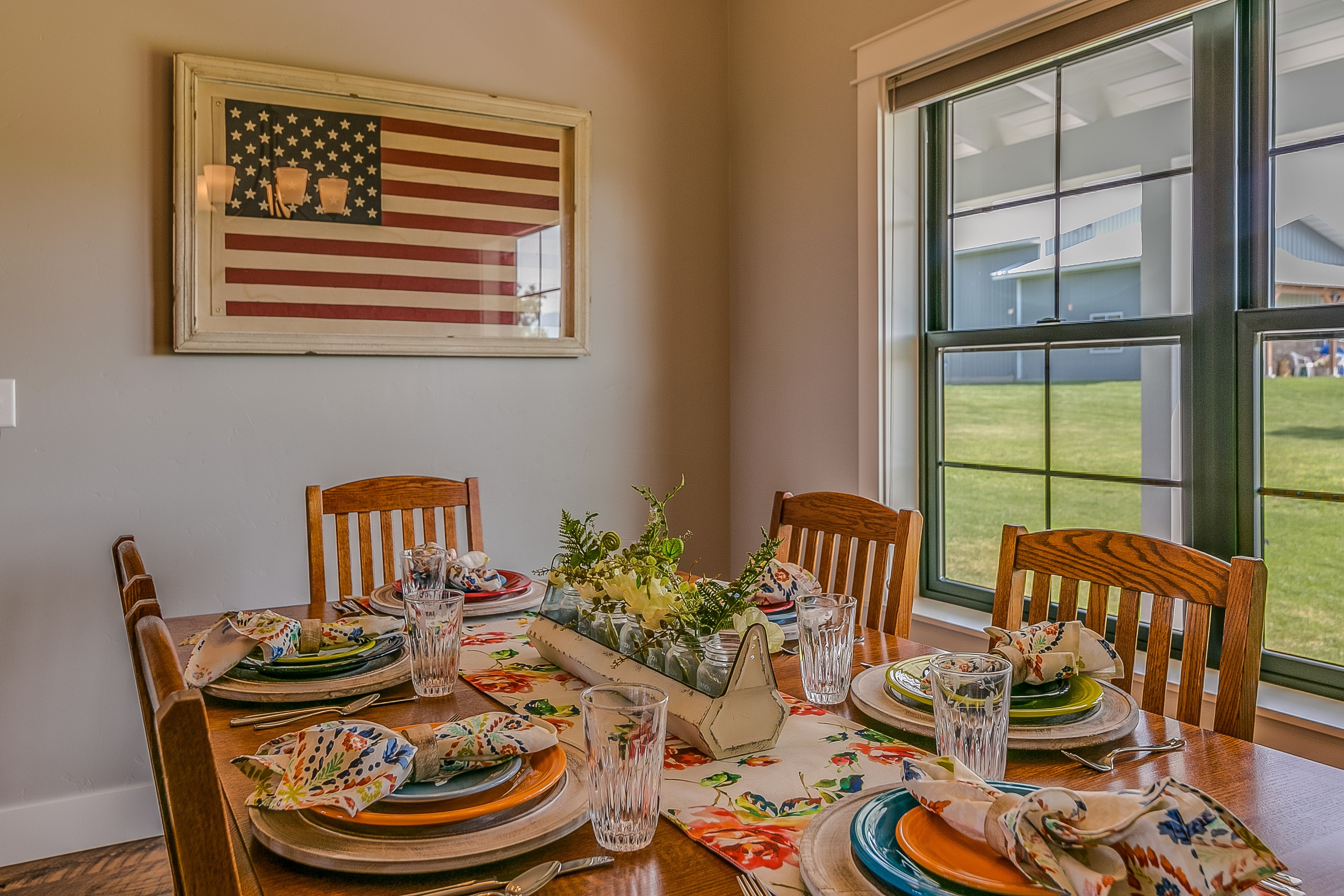 Dining country   with a acceptable   array  featuring colorful plates and napkins. An American emblem  is framed connected  the wall. Large model   shows an outdoor view