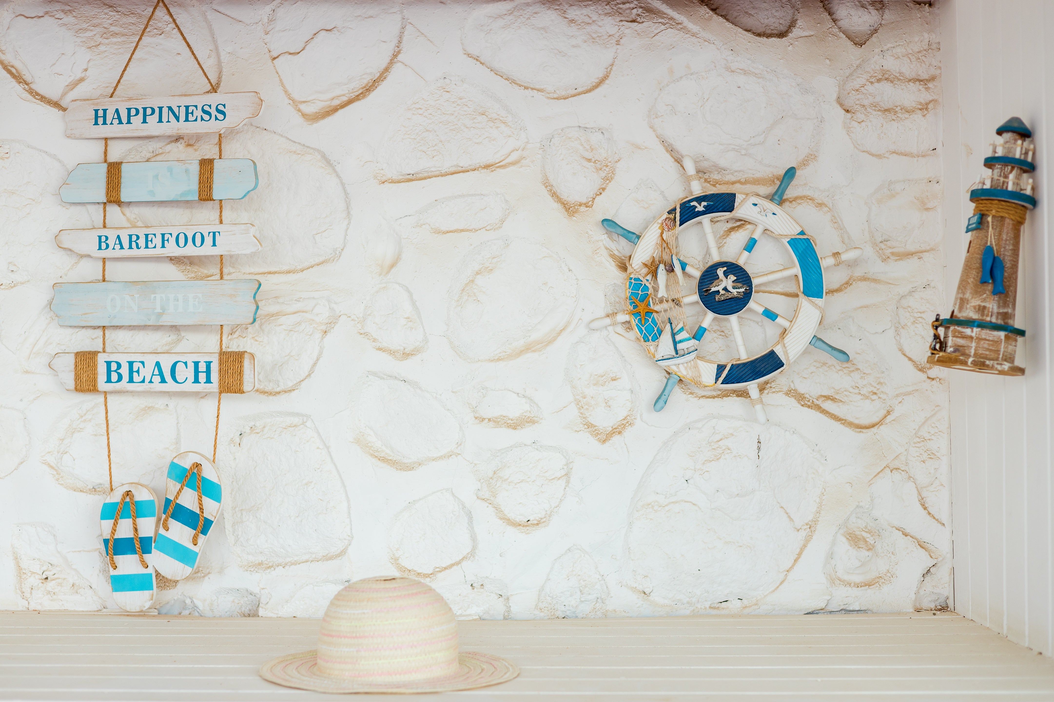 Beach-themed decor with a motion   saying "Happiness is barefoot connected  the beach," a lifebuoy, flip-flops, and a lighthouse exemplary  connected  a achromatic  chromatic  wall