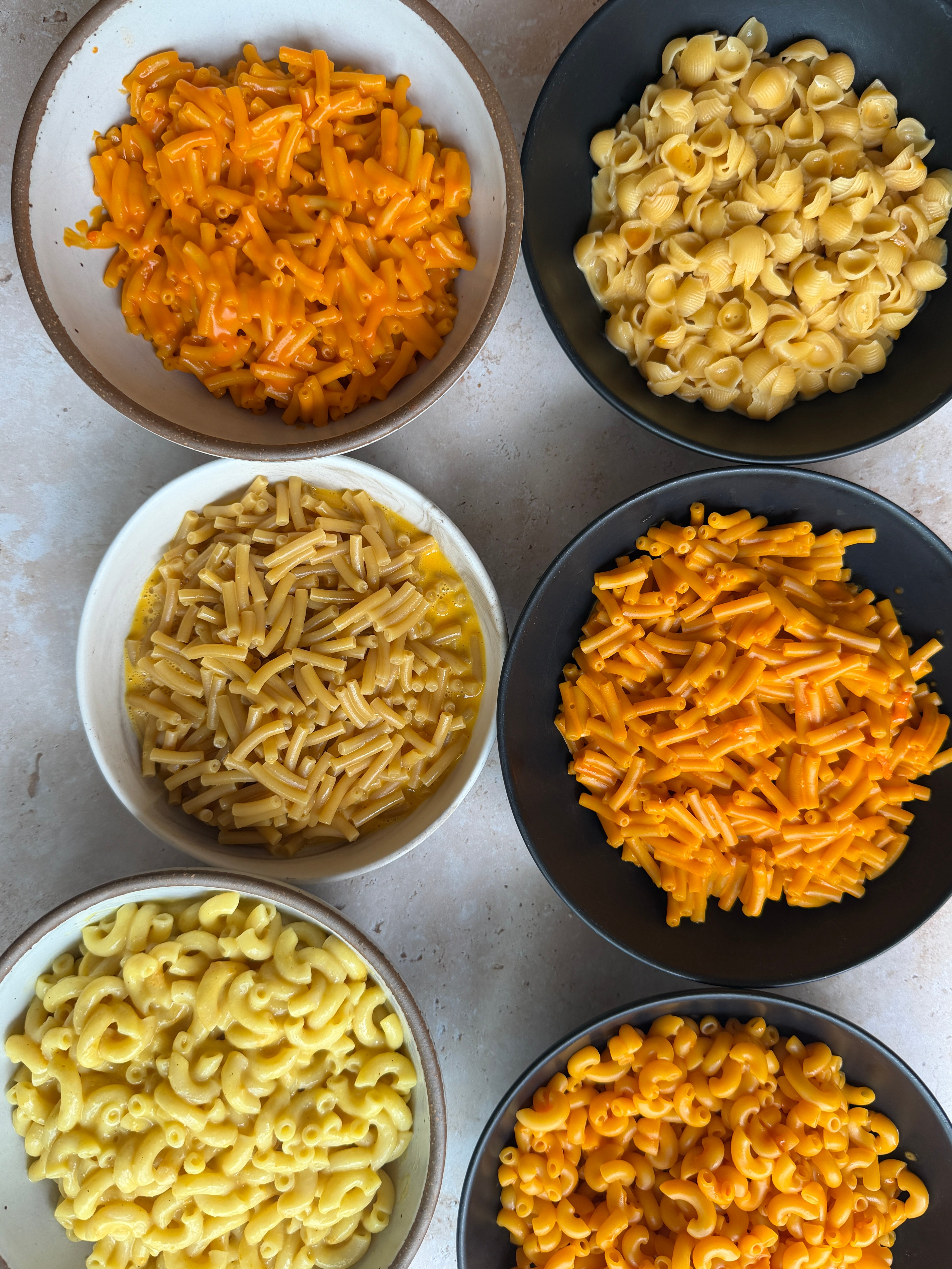Variety of pasta shapes in bowls, including macaroni, shells, and penne