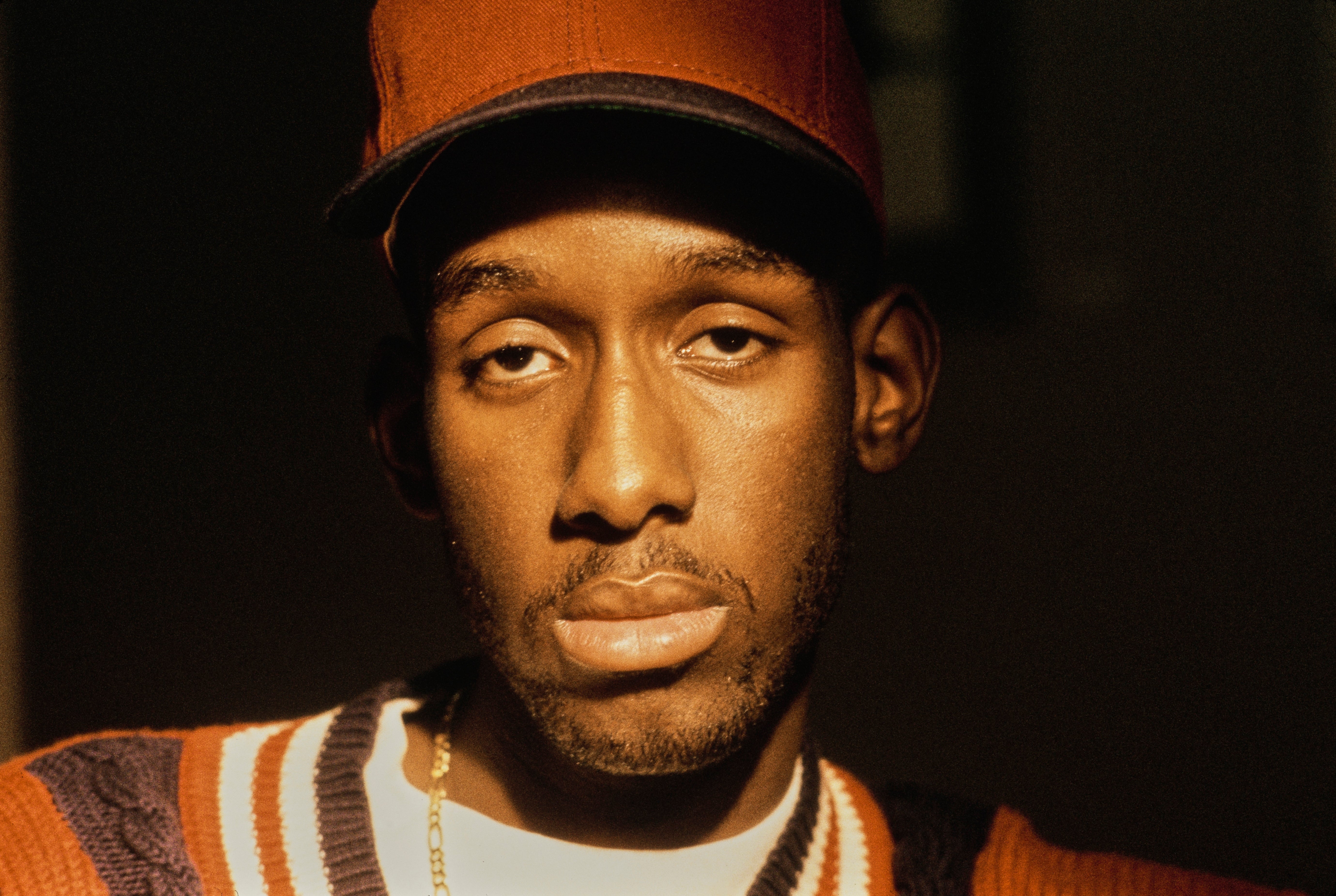 A idiosyncratic wearing a headdress and a striped sweater looks straight astatine the camera with a neutral expression