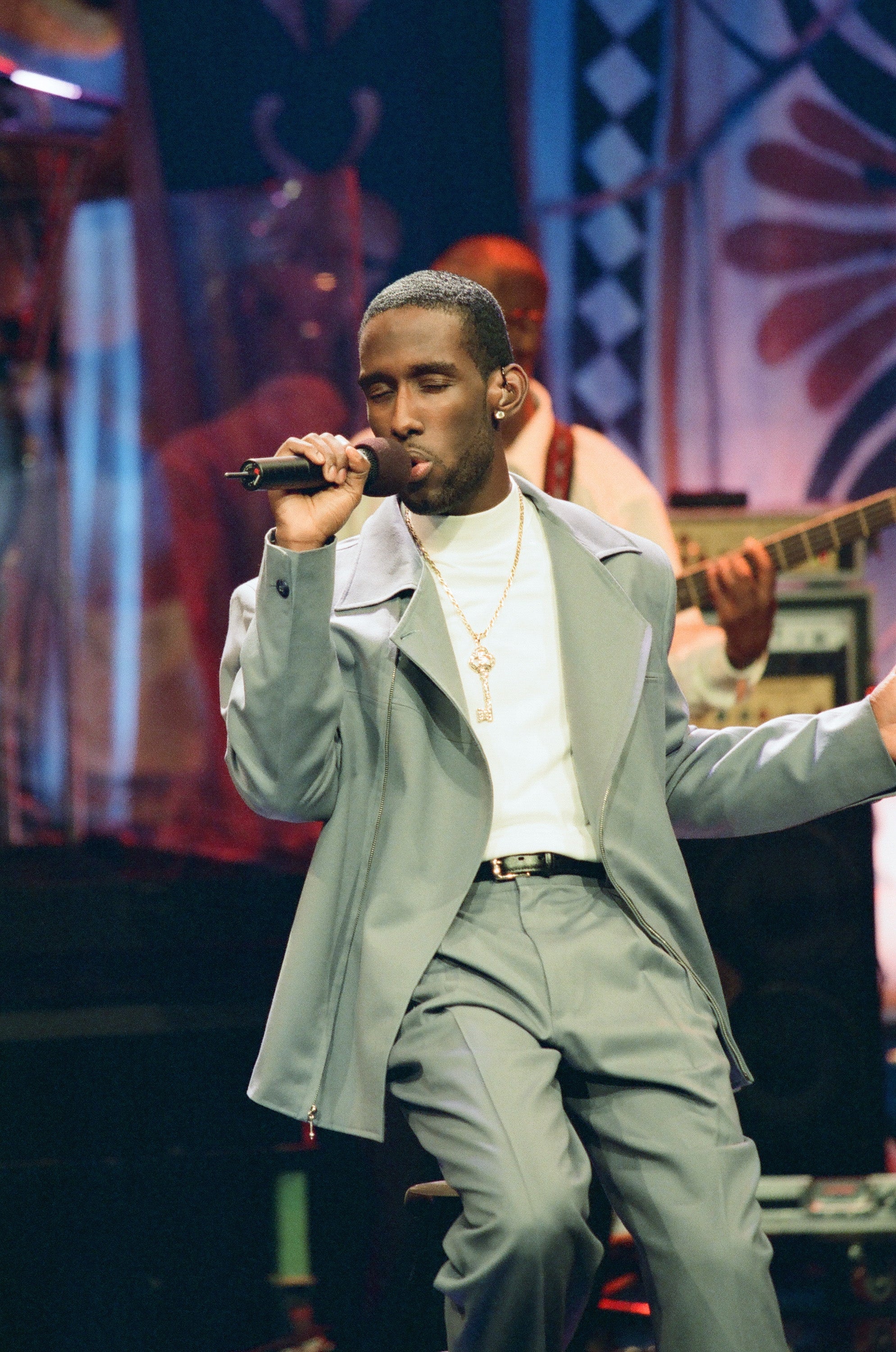 Singer performs connected signifier successful stylish suit, eyes closed, holding a microphone