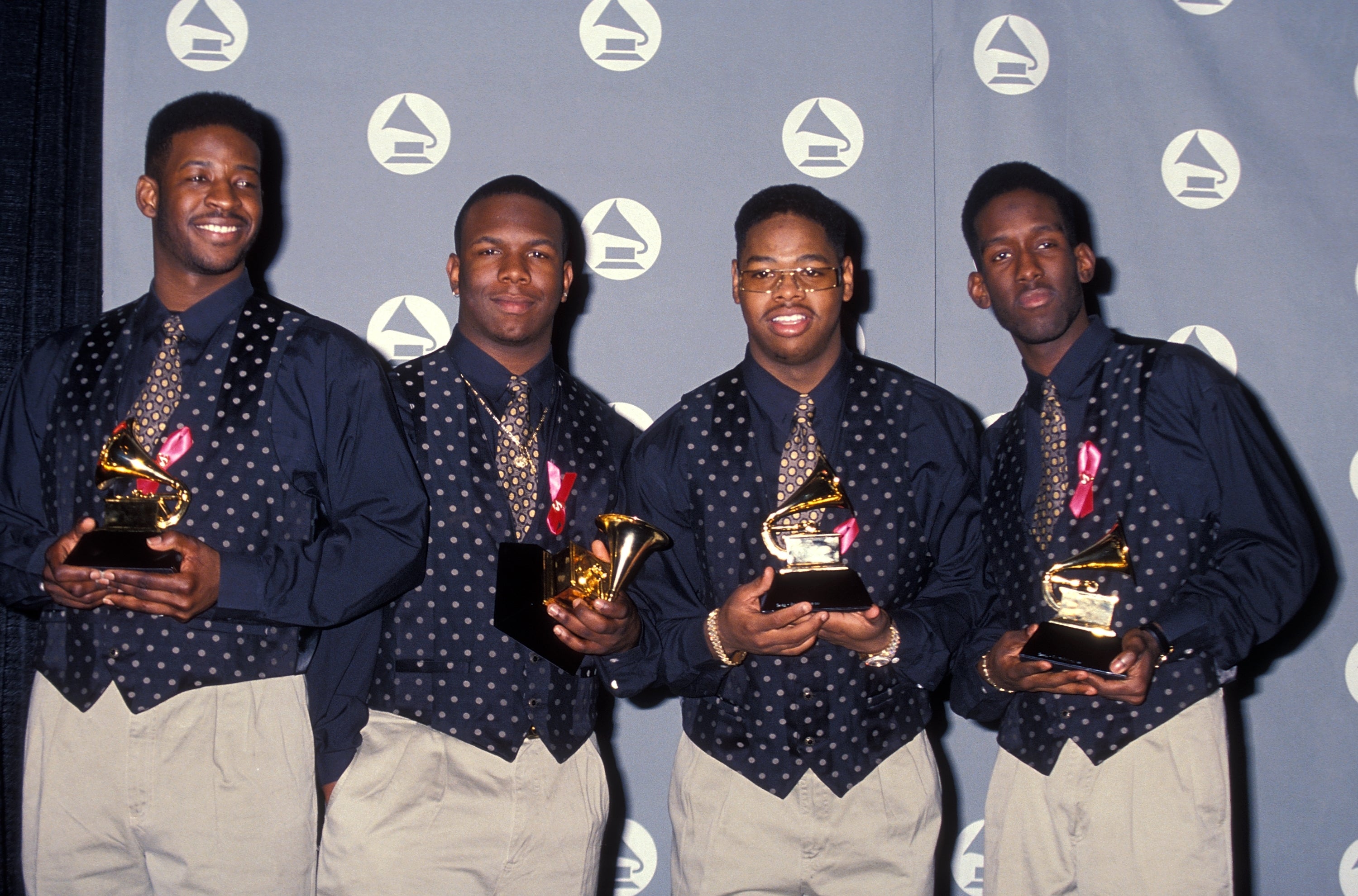 Four individuals holding Grammy Awards, dressed successful coordinated polka dot shirts and ties, posing astatine a Grammy ceremonial backdrop