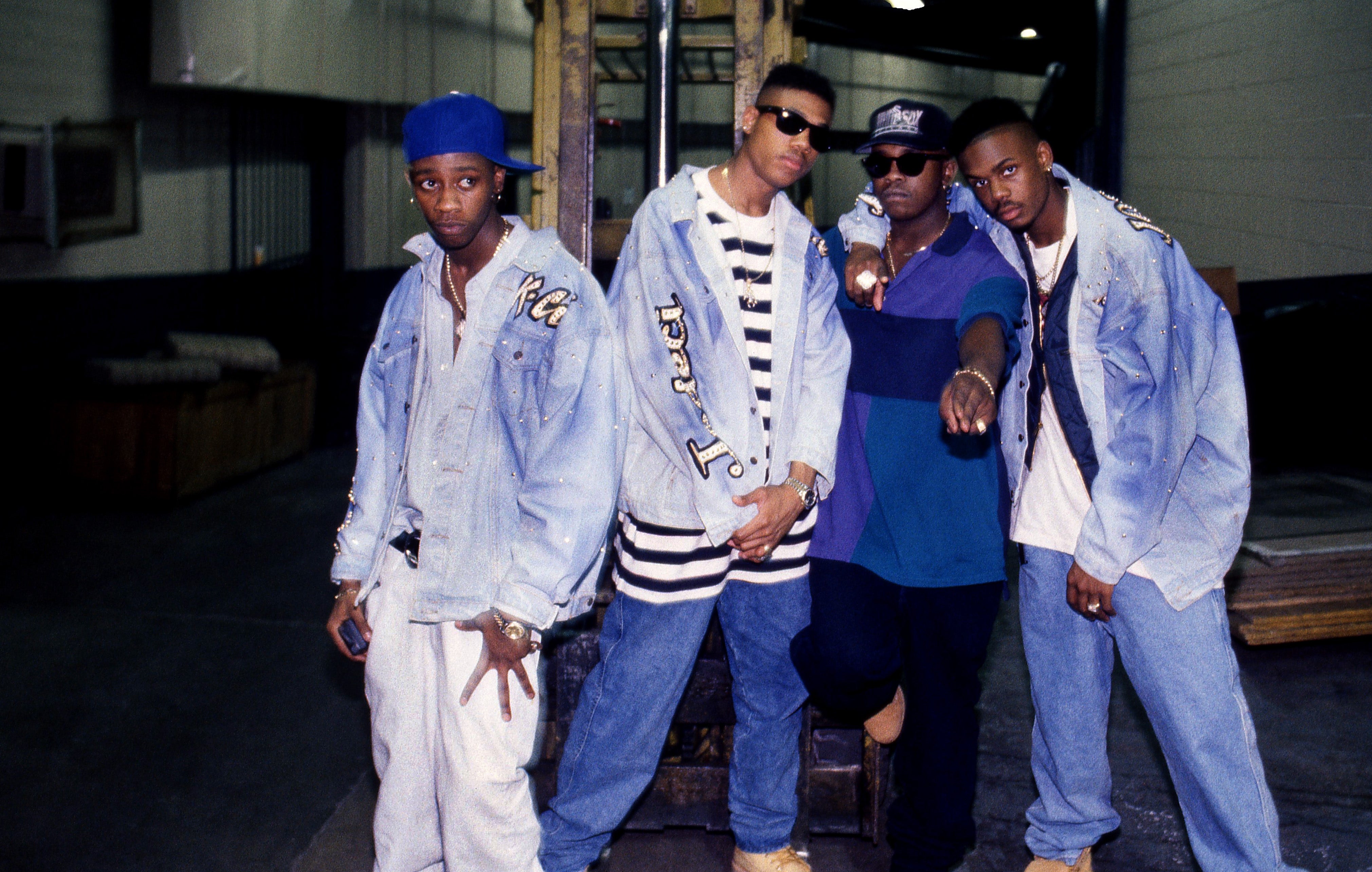 Four individuals successful denim outfits airs casually, 1 points towards the camera. They deterioration hats and boots, embodying 90s municipality style