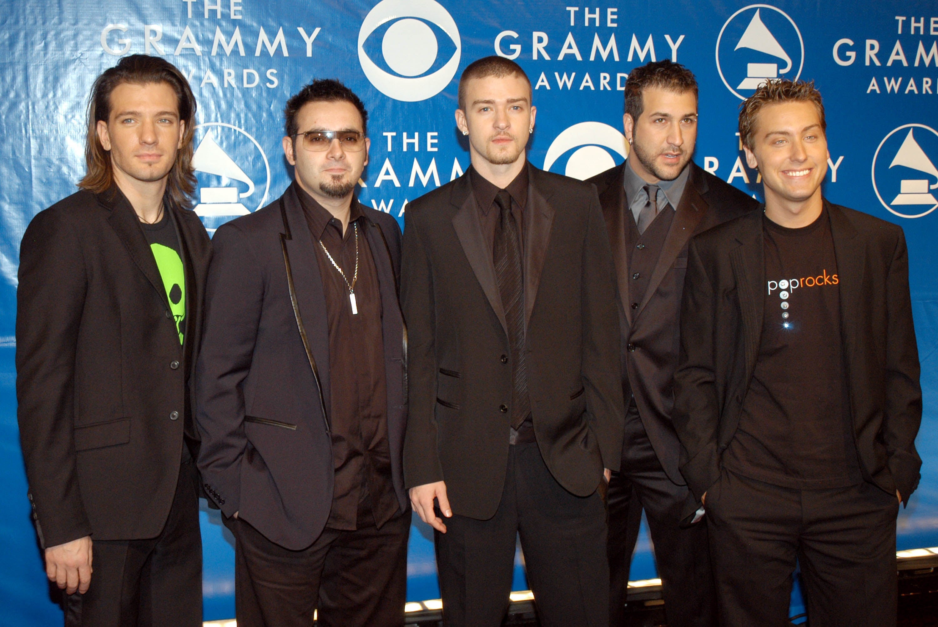 Five men successful suits airs connected the Grammy Awards reddish carpet successful beforehand of a step-and-repeat banner