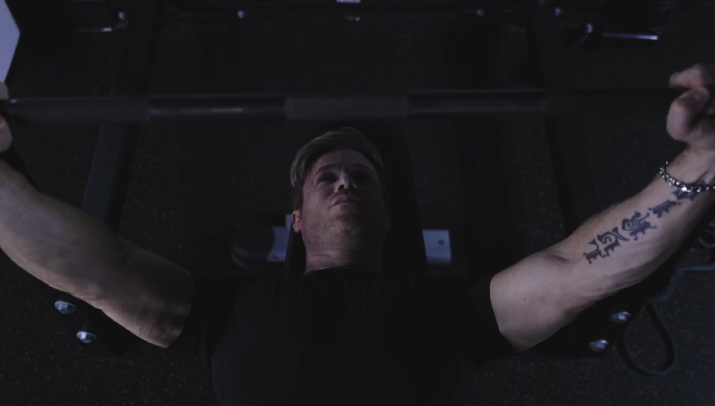 Person lifting weights connected a seat press, showing spot and focus. Tattoo disposable connected their arm