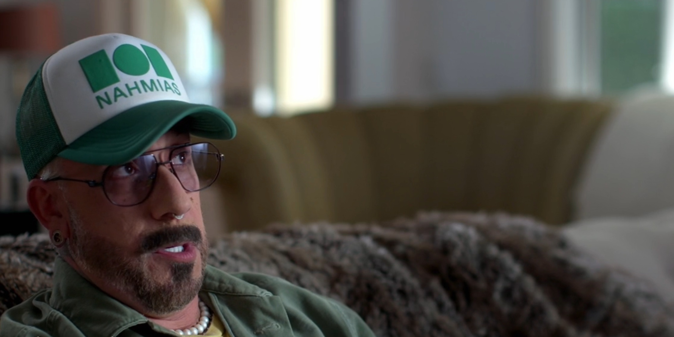 Person successful a headdress and glasses sitting connected a couch, speaking successful an interview. Text identifies them arsenic Alexander McLean, artist, Backstreet Boys