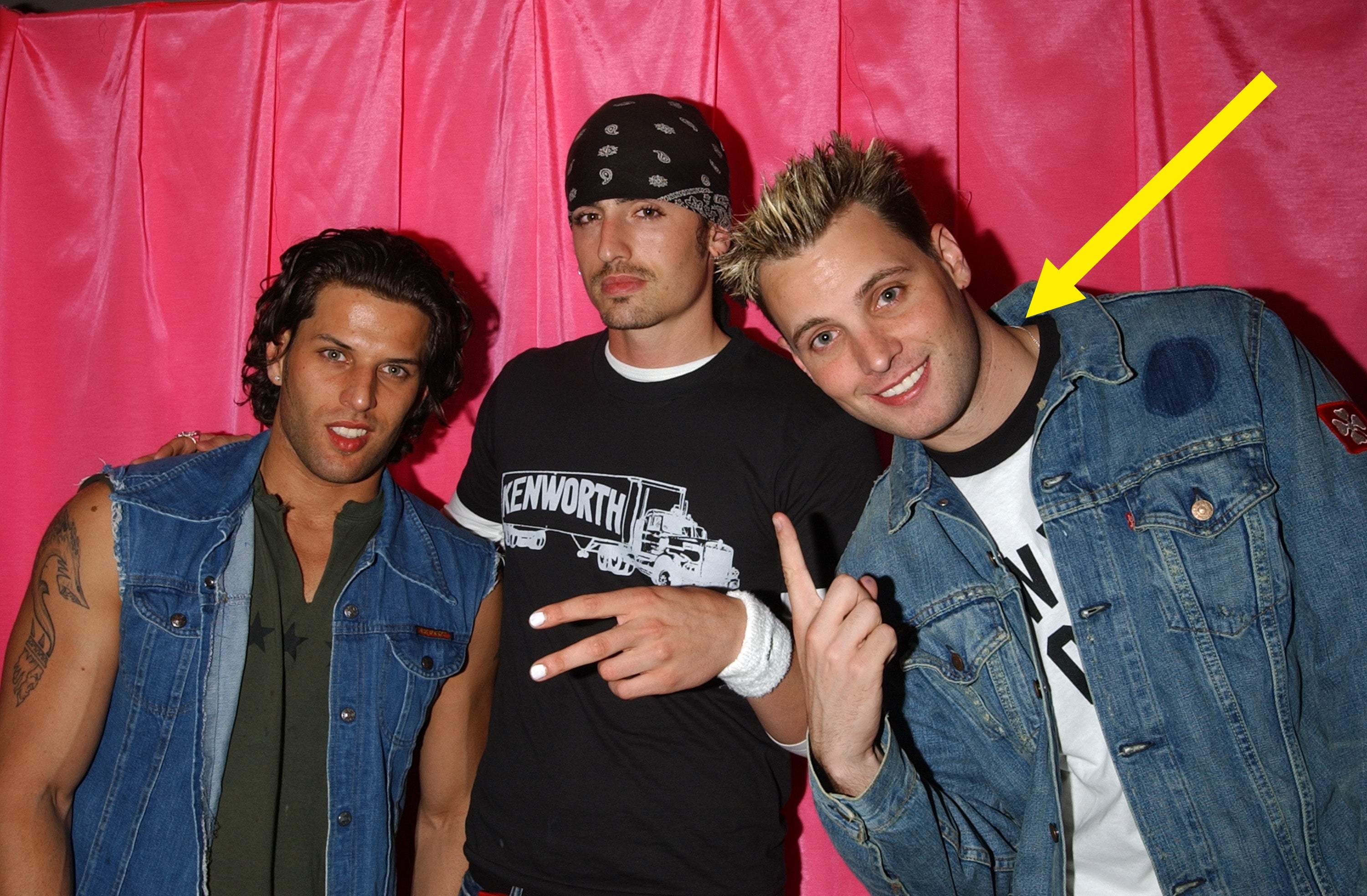 Three individuals airs successful casual denim and t-shirts against a textured backdrop. Two amusement bid signs, conveying a relaxed vibe