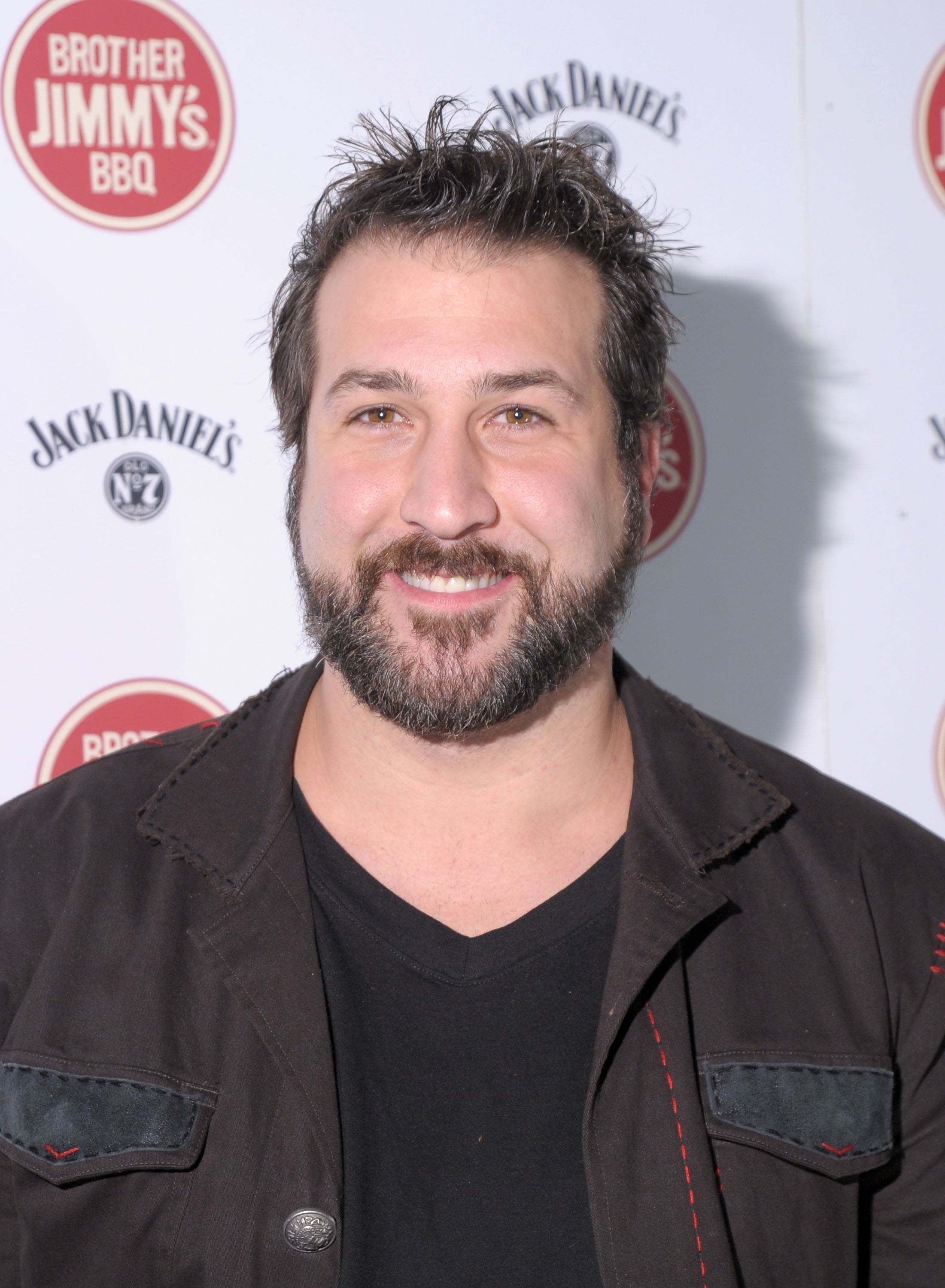 A idiosyncratic with a beard smiles astatine an event. They deterioration a achromatic garment and jacket