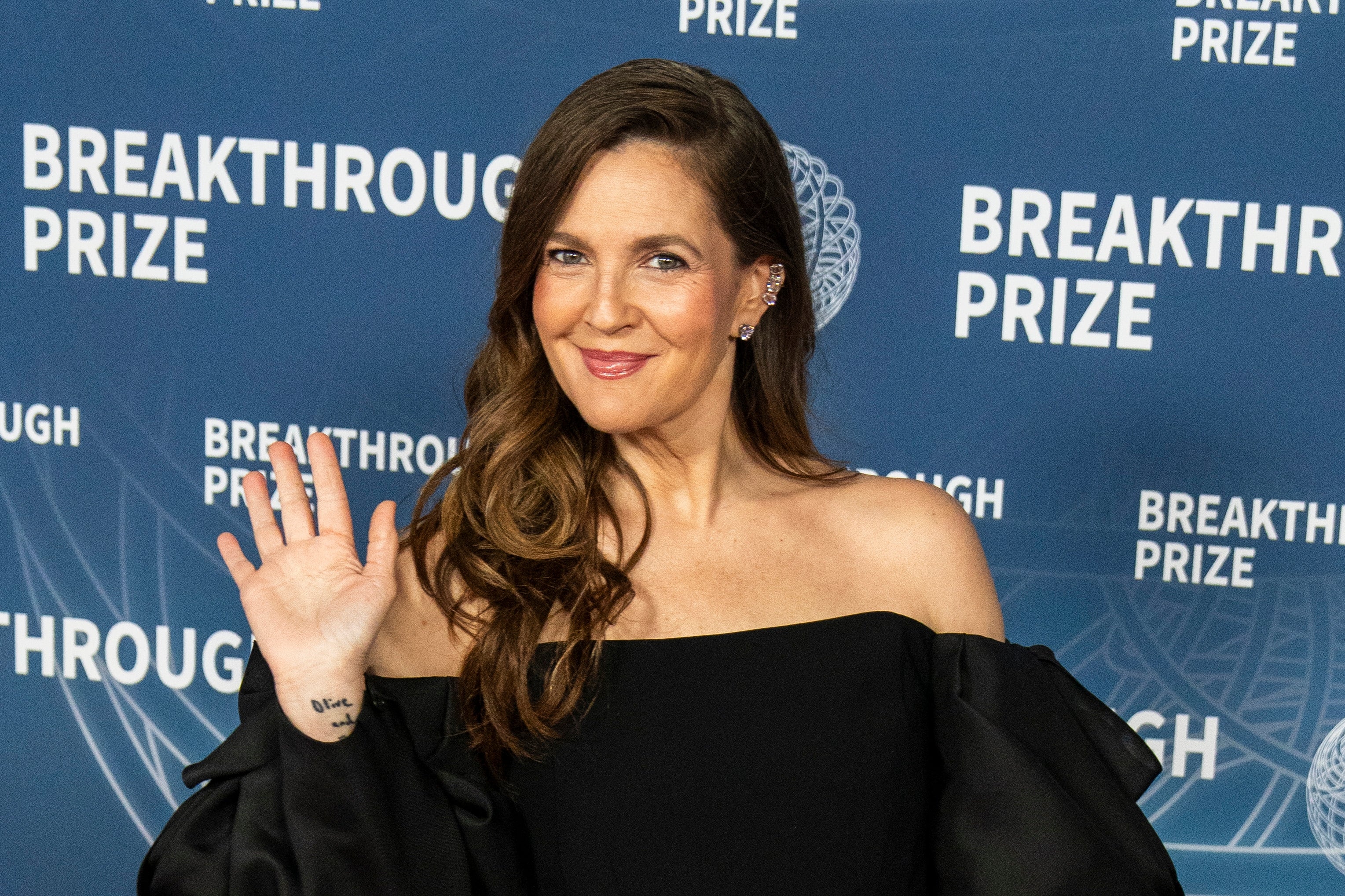 Drew Barrymore waving connected  a reddish  carpet