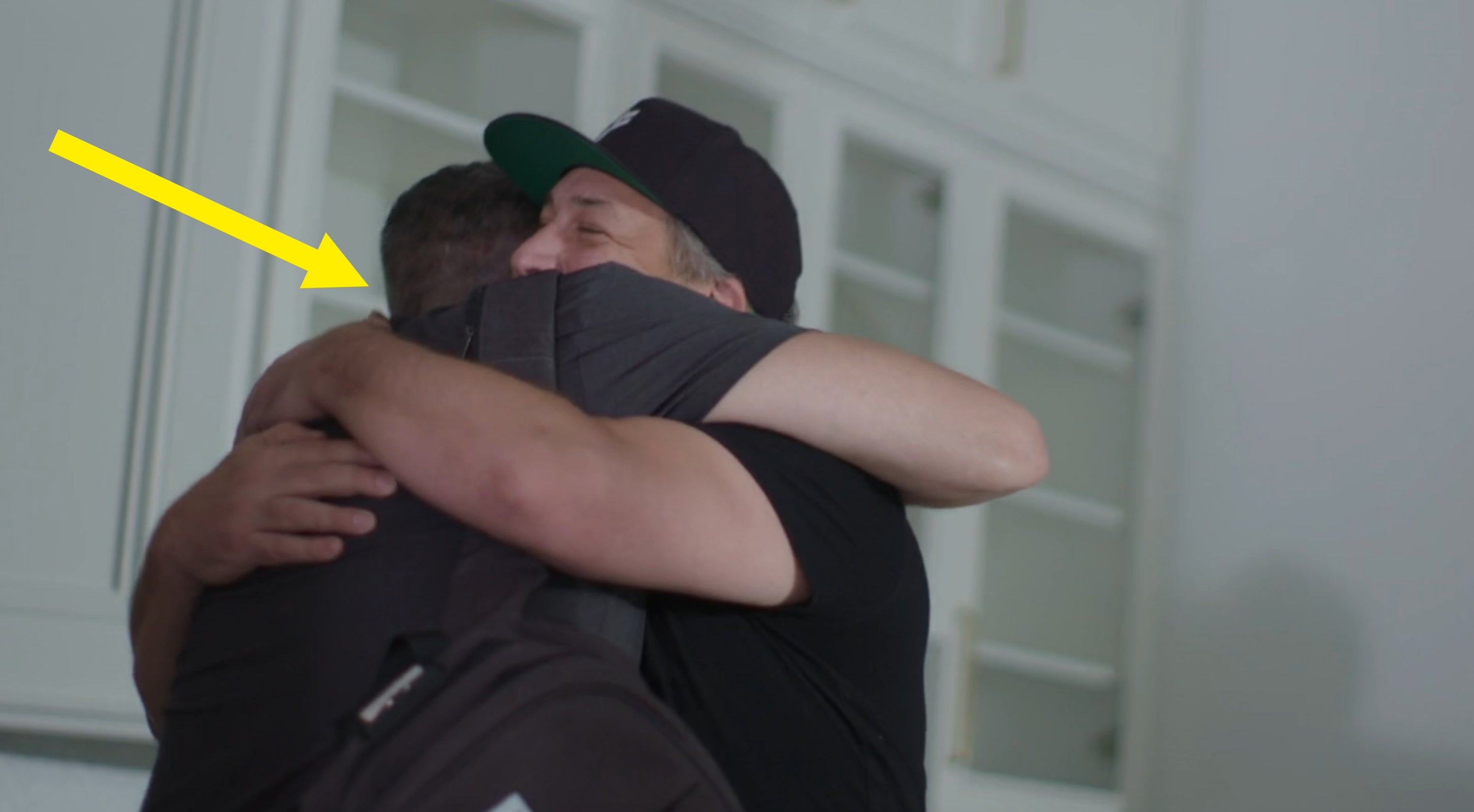 Two radical hugging warmly successful a cozy setting. One is wearing a headdress and backpack, adding a casual vibe