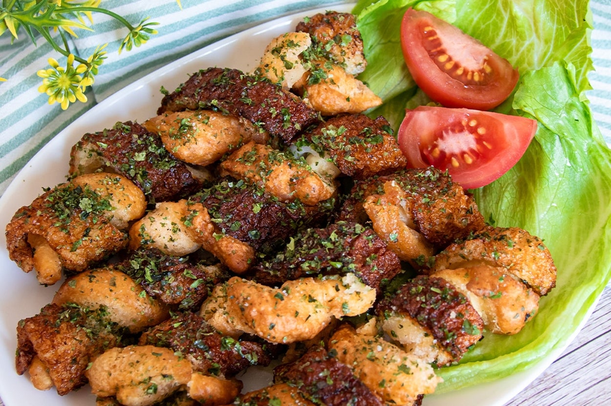 皿に盛られたちくわ料理。レタスとトマトが添えられ、花の飾りが横にある。