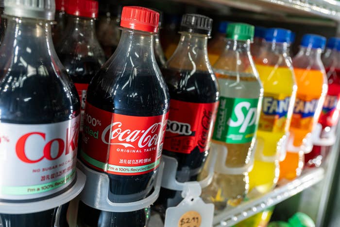 Plastic bottles of assorted  sodas, including Diet Coke and Coca-Cola, displayed connected  a store   shelf
