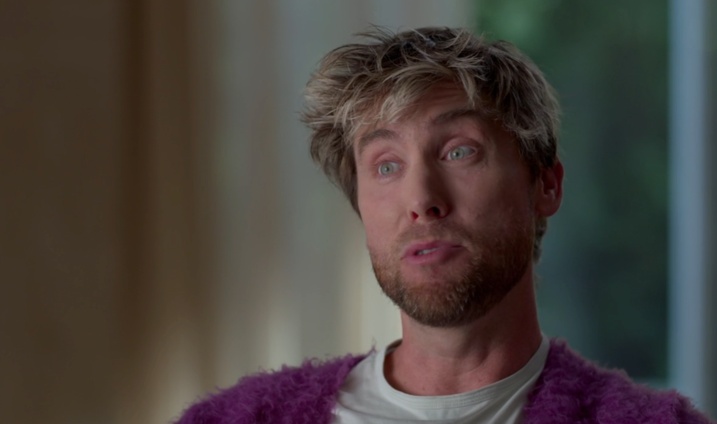 Person wearing a shaggy cardigan and t-shirt, speaking successful an interrogation setting