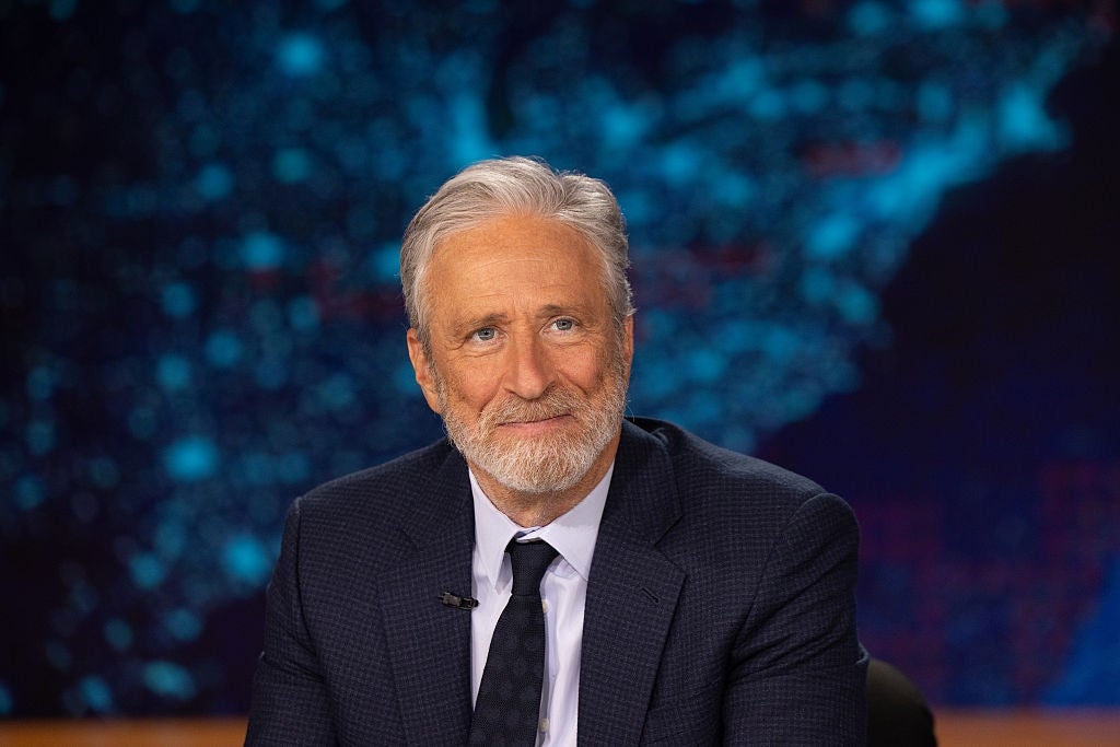 Smiling idiosyncratic successful a suit sits astatine a quality desk, representation successful the background