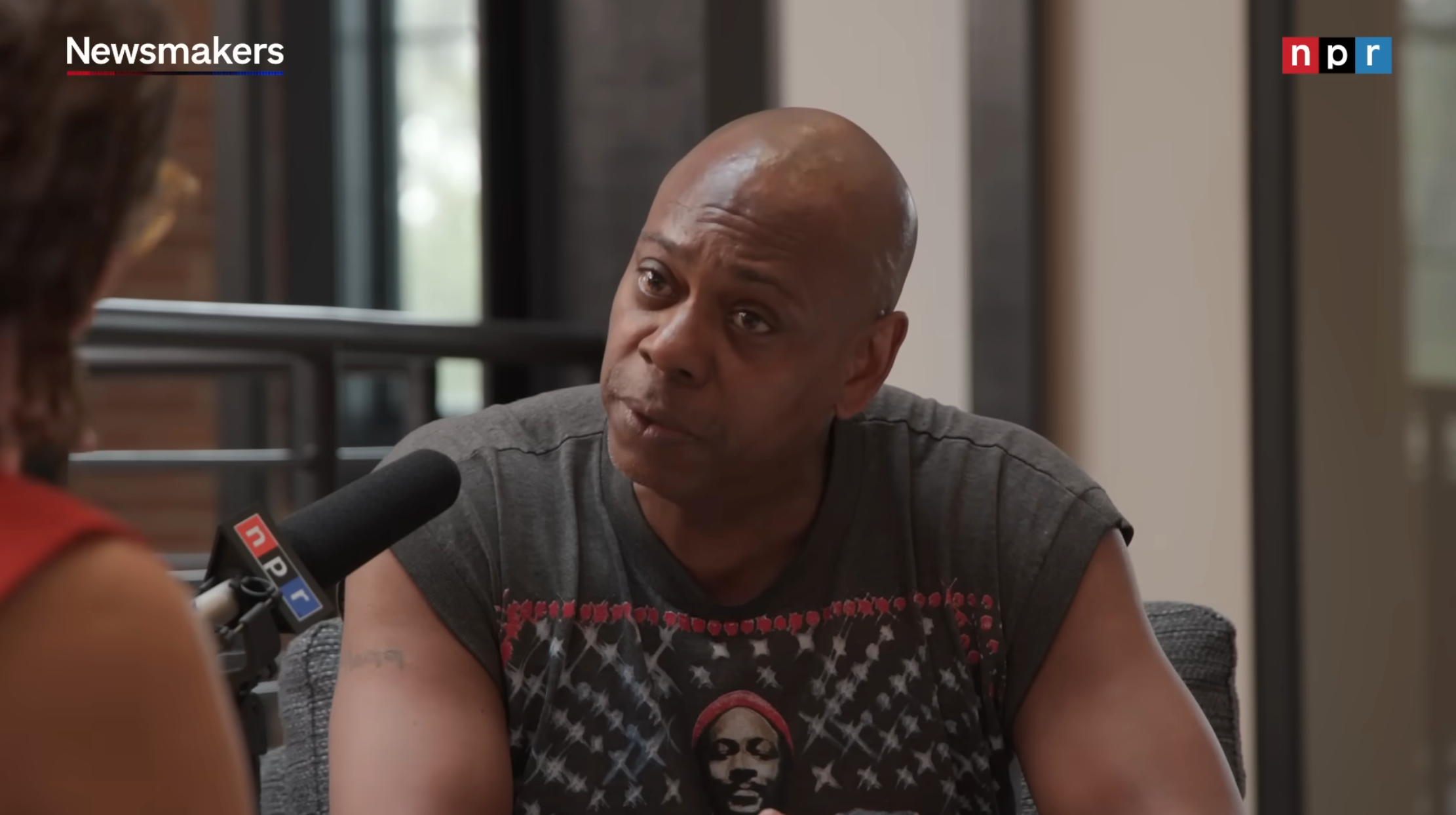 Person successful  a casual graphic tee is speaking into an NPR microphone during an interview