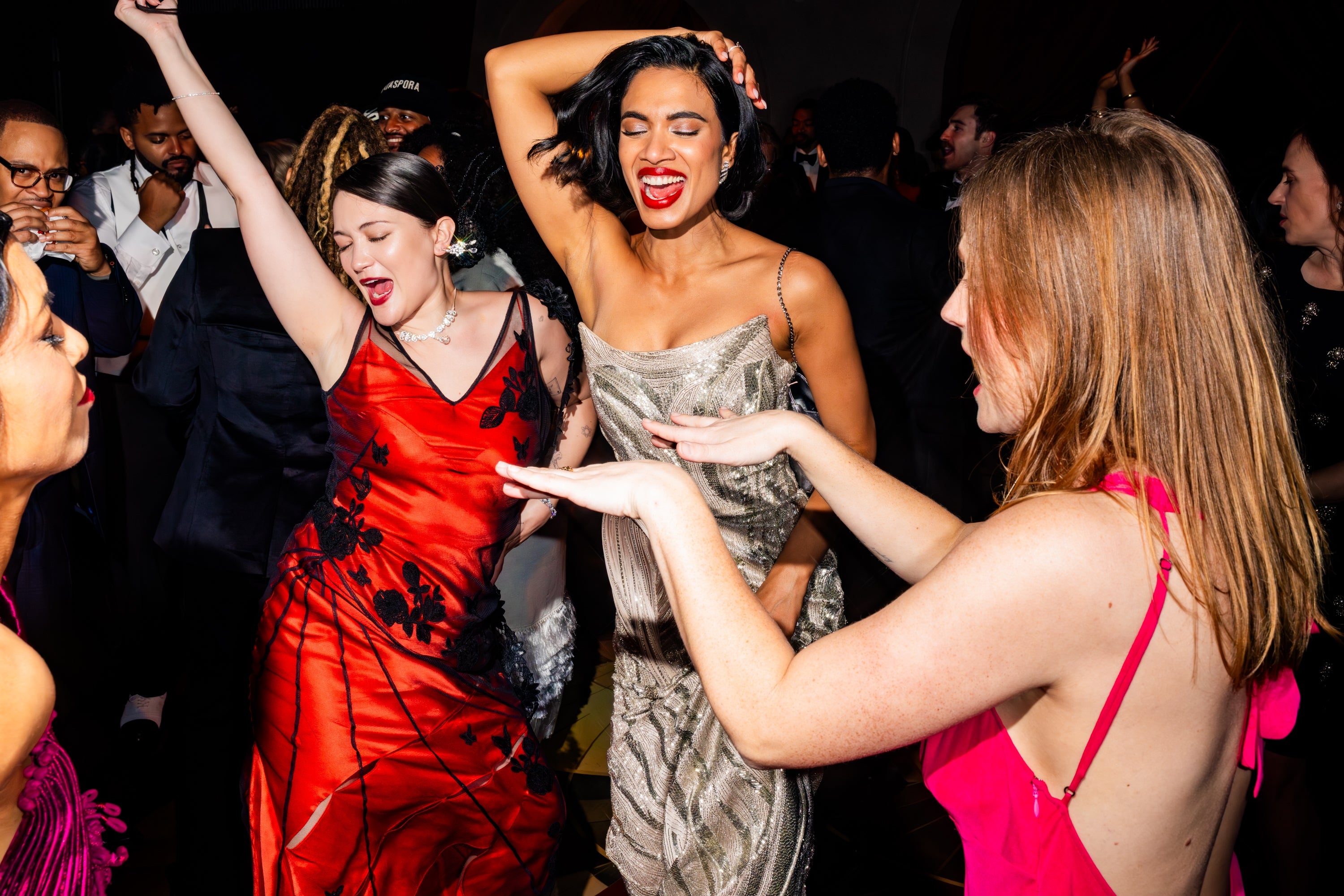 People dancing energetically astatine  a lively event, wearing elegant evening dresses, with joyful expressions and vibrant movements