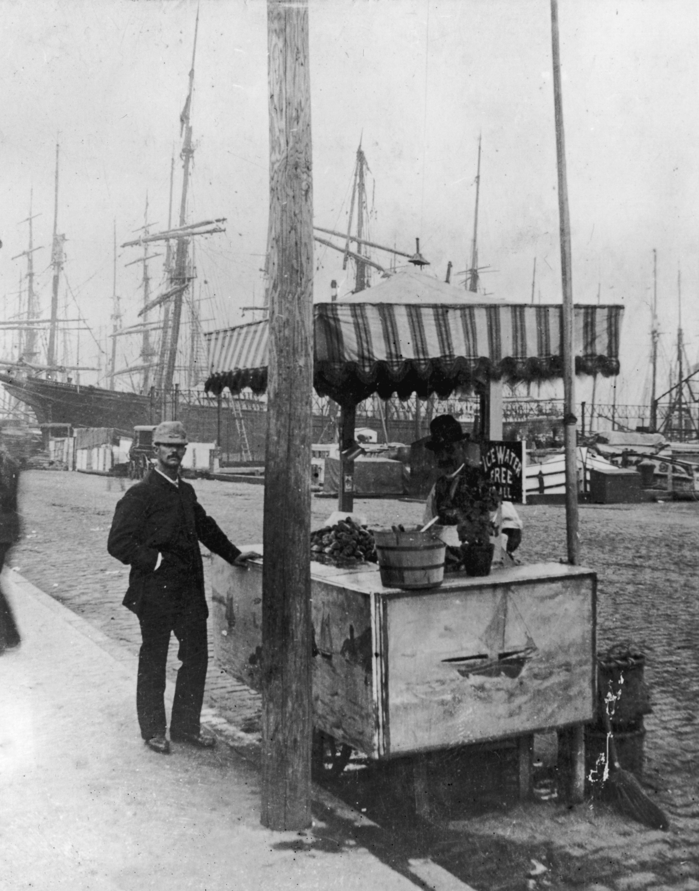 A vintage thoroughfare  vendor with a cart connected  a dockside, ample  ships successful  the background, and a lawsuit    successful  a suit   and hat