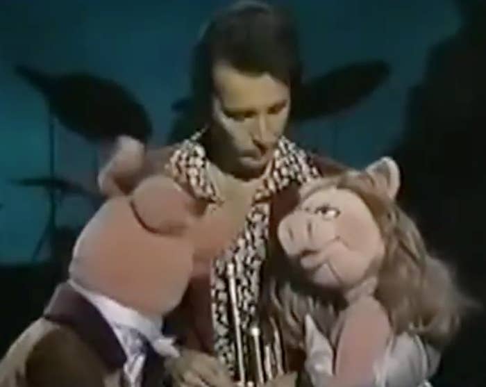 A antheral   plays the trumpet connected  signifier    with 2  pig puppets successful  stylish outfits beside him, emblematic  of a retro show  scene