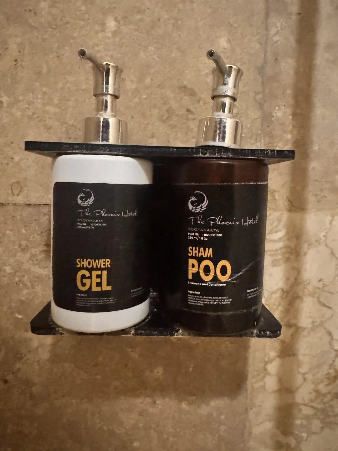 Two soap dispensers connected  a shelf, labeled "Shower Gel" and "Sham Poo," perchance   humorous owed  to the alternate spelling