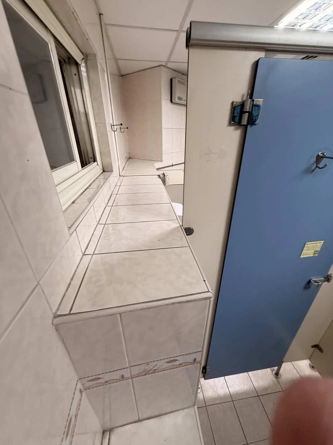 Public bath  with a precocious   ledge obstructing entree  to an unfastened  stall