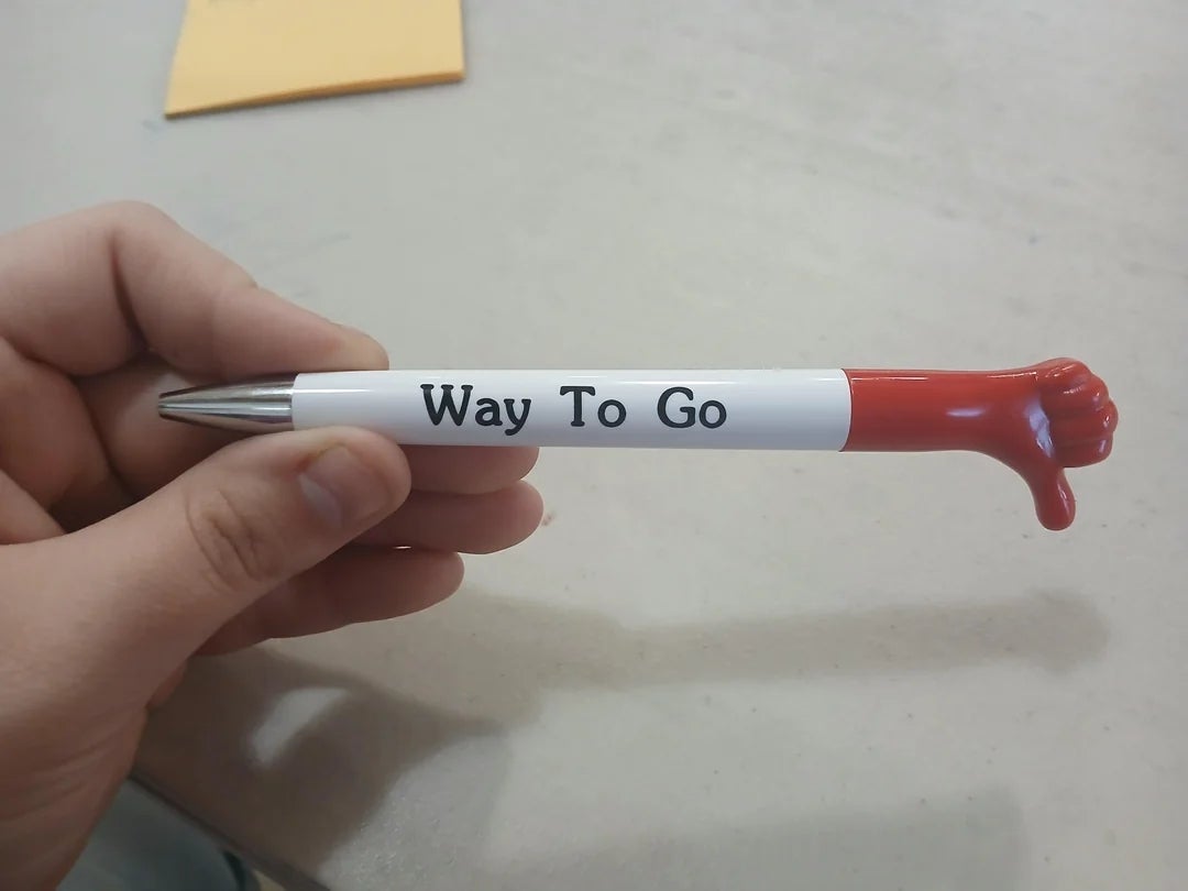 Novelty pen with a tiny red thumbs-down hand on top, labeled 