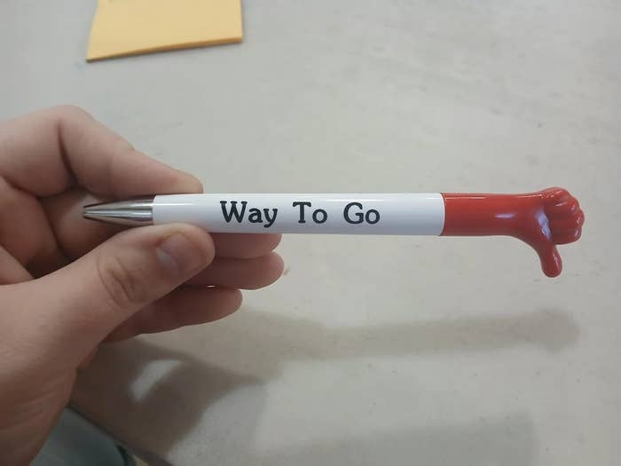 Novelty pen with a tiny   reddish  thumbs-down manus  connected  top, labeled "Way To Go."
