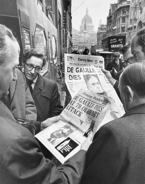 People gather in a London street reading a newspaper headline about the death of de Gaulle
