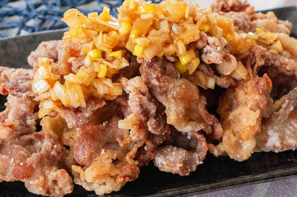 皿に盛られた揚げた鶏の唐揚げに刻んだネギがトッピングされています。