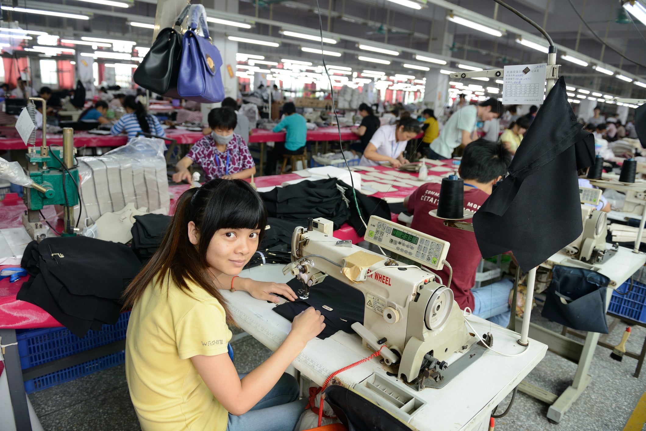 A mill  idiosyncratic    sewing cloth  astatine  a machine, surrounded by colleagues moving   astatine  akin  stations