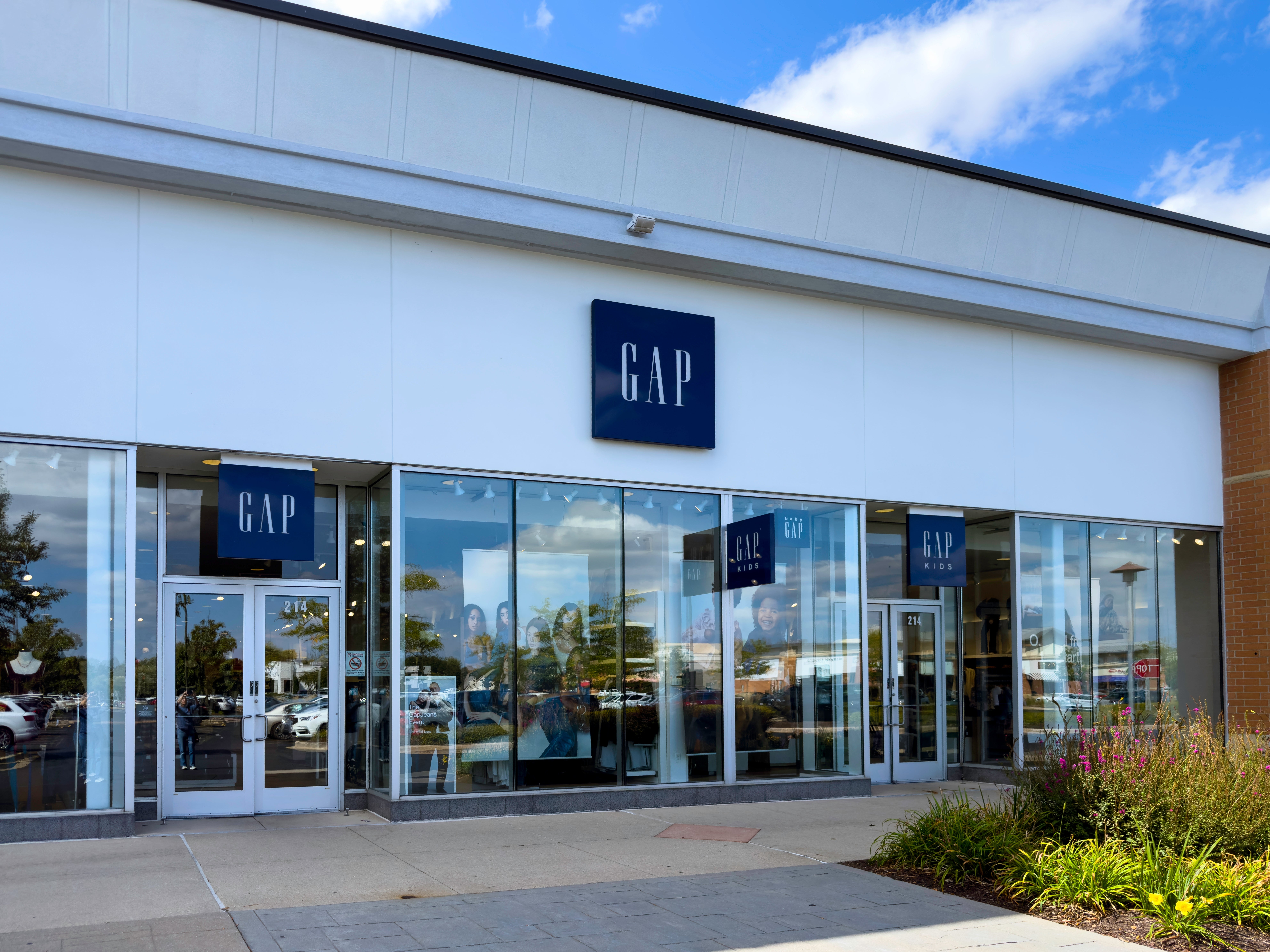 Front view of a Gap store with glass doors and windows, displaying clothing items inside