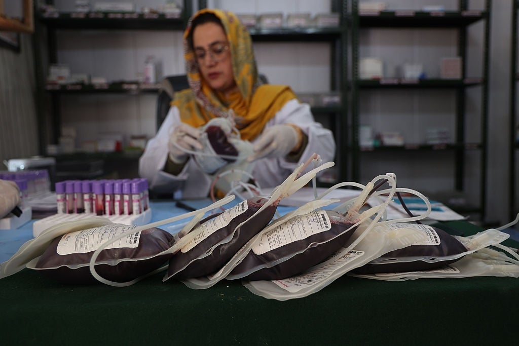 A pistillate   successful  a laboratory  overgarment  and headscarf works   with humor  bags connected  a table, focused connected  aesculapian  tasks