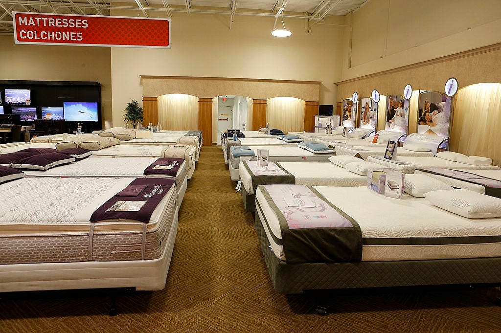 Showroom filled with assorted  mattresses arranged neatly, featuring signs successful  English and Spanish speechmaking  "MATTRESSES" and "COLCHONES."