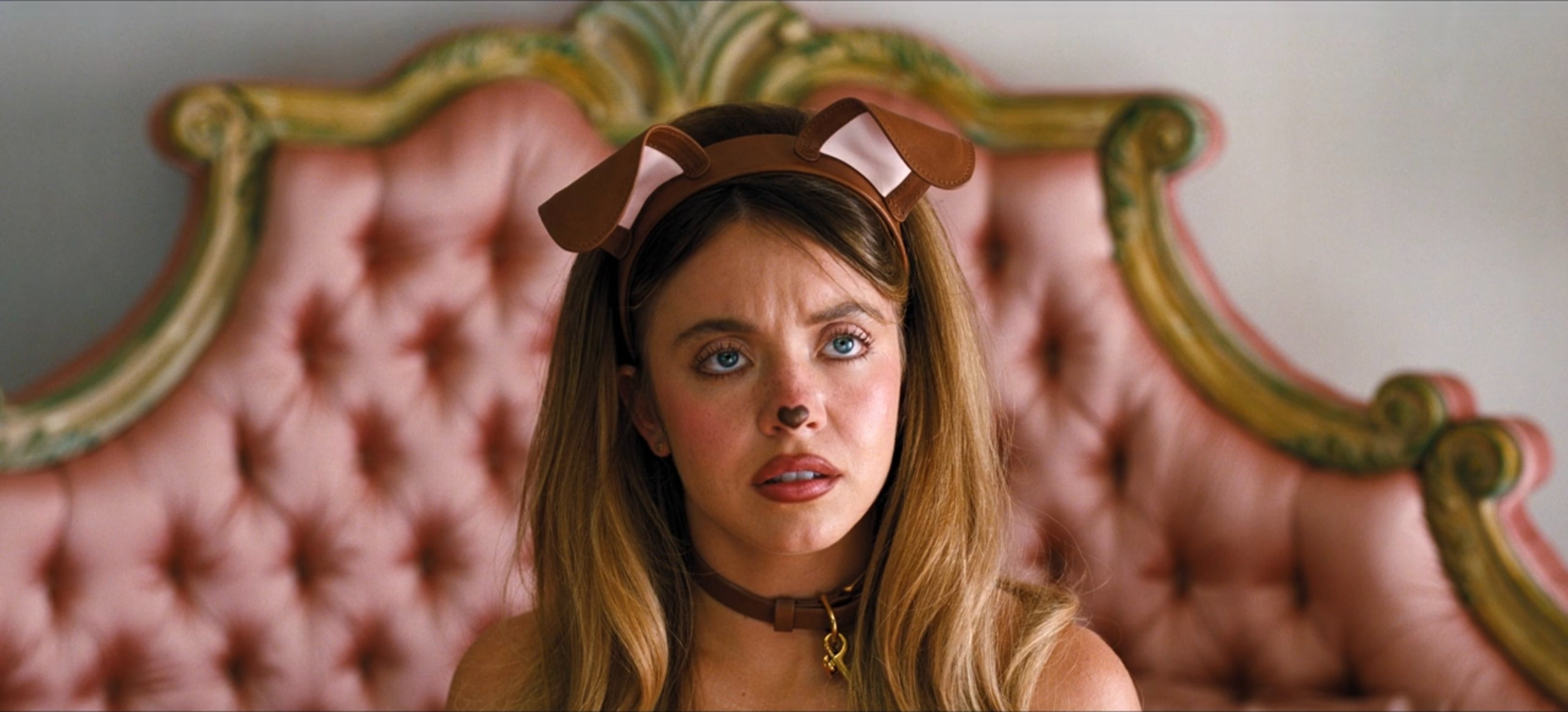 Person with long hair wearing dog ears headband and collar, sitting on ornate chair