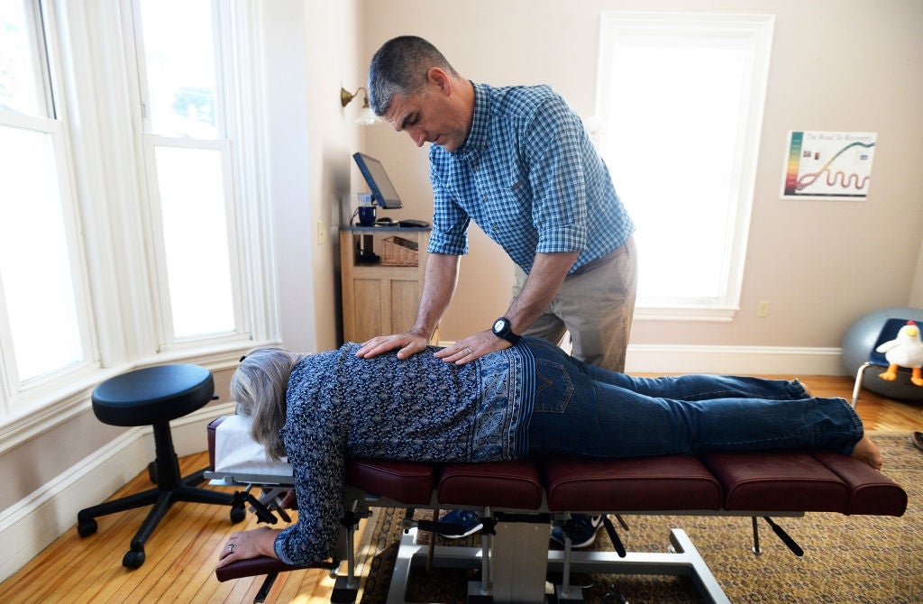 A chiropractor adjusts a patient's backmost  successful  a attraction    country   with a massage array  and a fewer  decorative elements connected  the wall