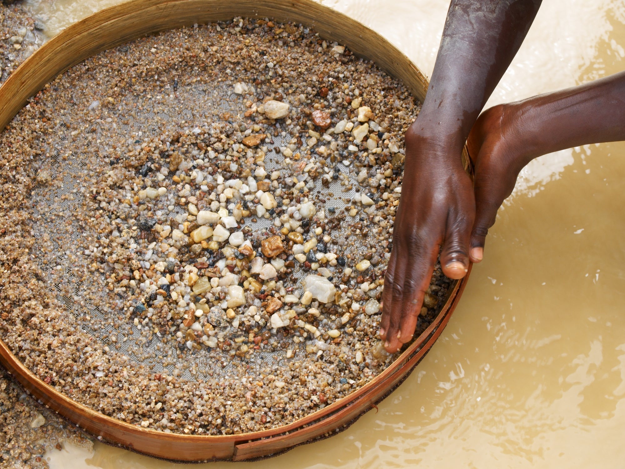 Hands sifting done  a circular  sieve filled with gravel and stones, apt  successful  a panning process   for sorting oregon  searching