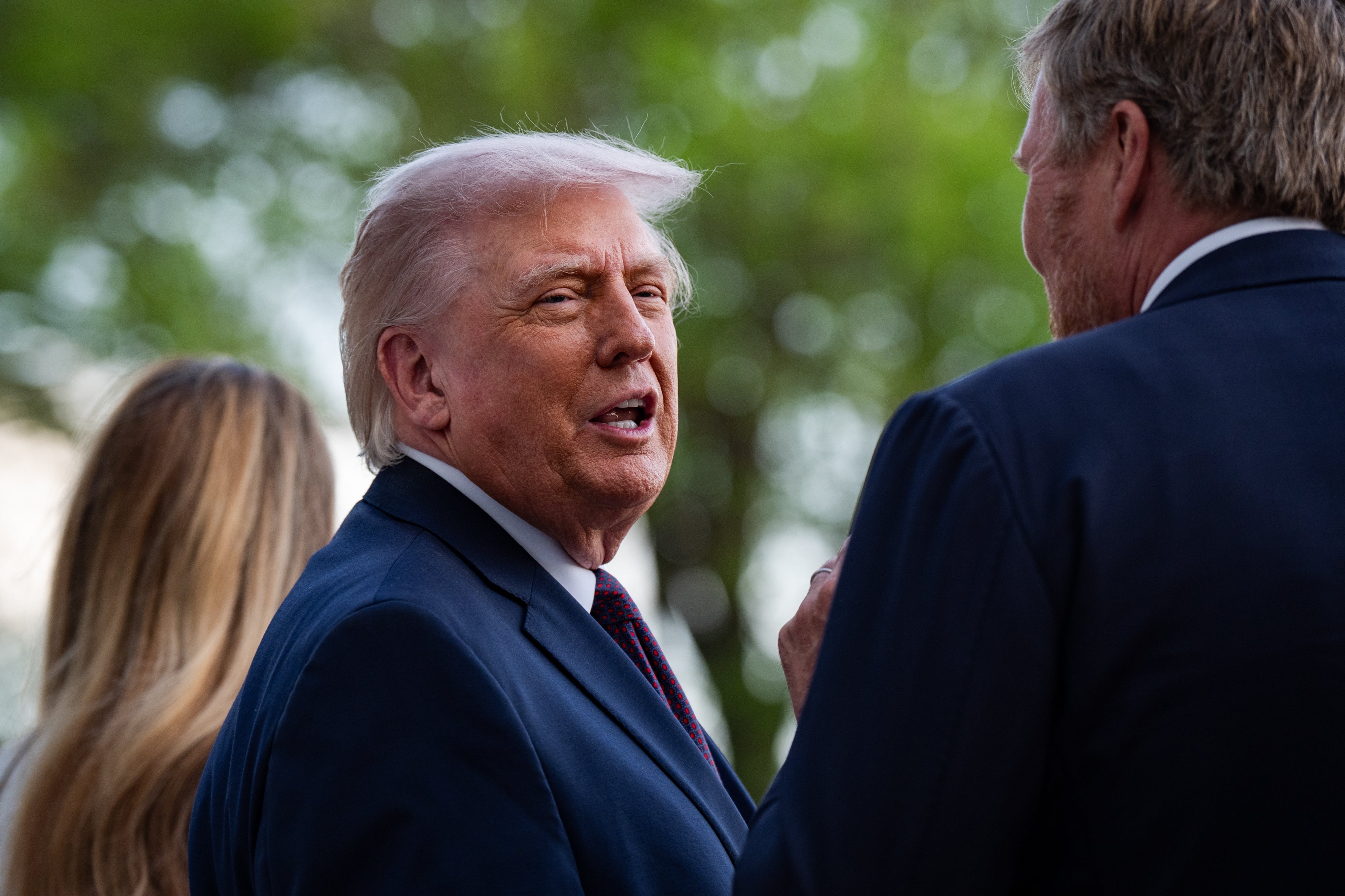 A idiosyncratic   successful  a suit   speaks with different  idiosyncratic  outdoors, with trees successful  the background