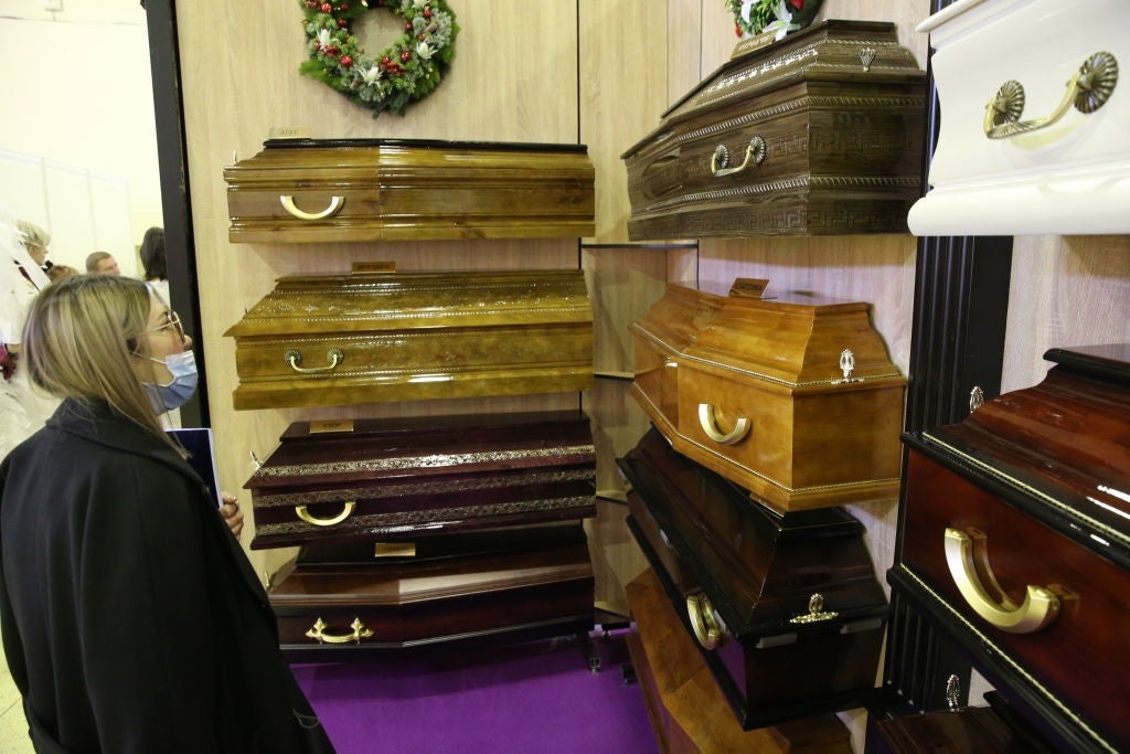 Person successful  disguise  observes a show  of assorted  woody  and metallic  caskets successful  a showroom