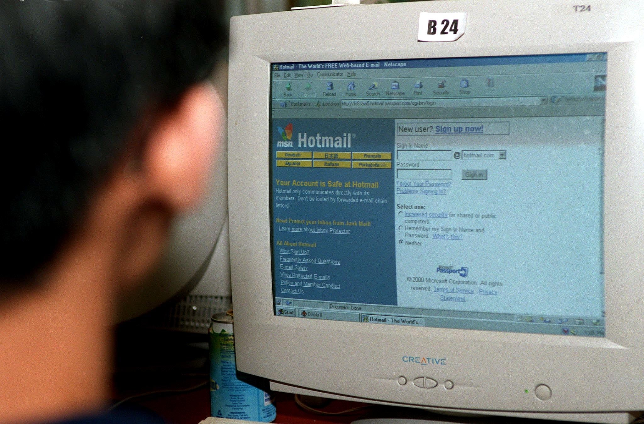 Person utilizing an aged  machine  with a CRT show   displaying the Hotmail login page, highlighting aboriginal  net  technology